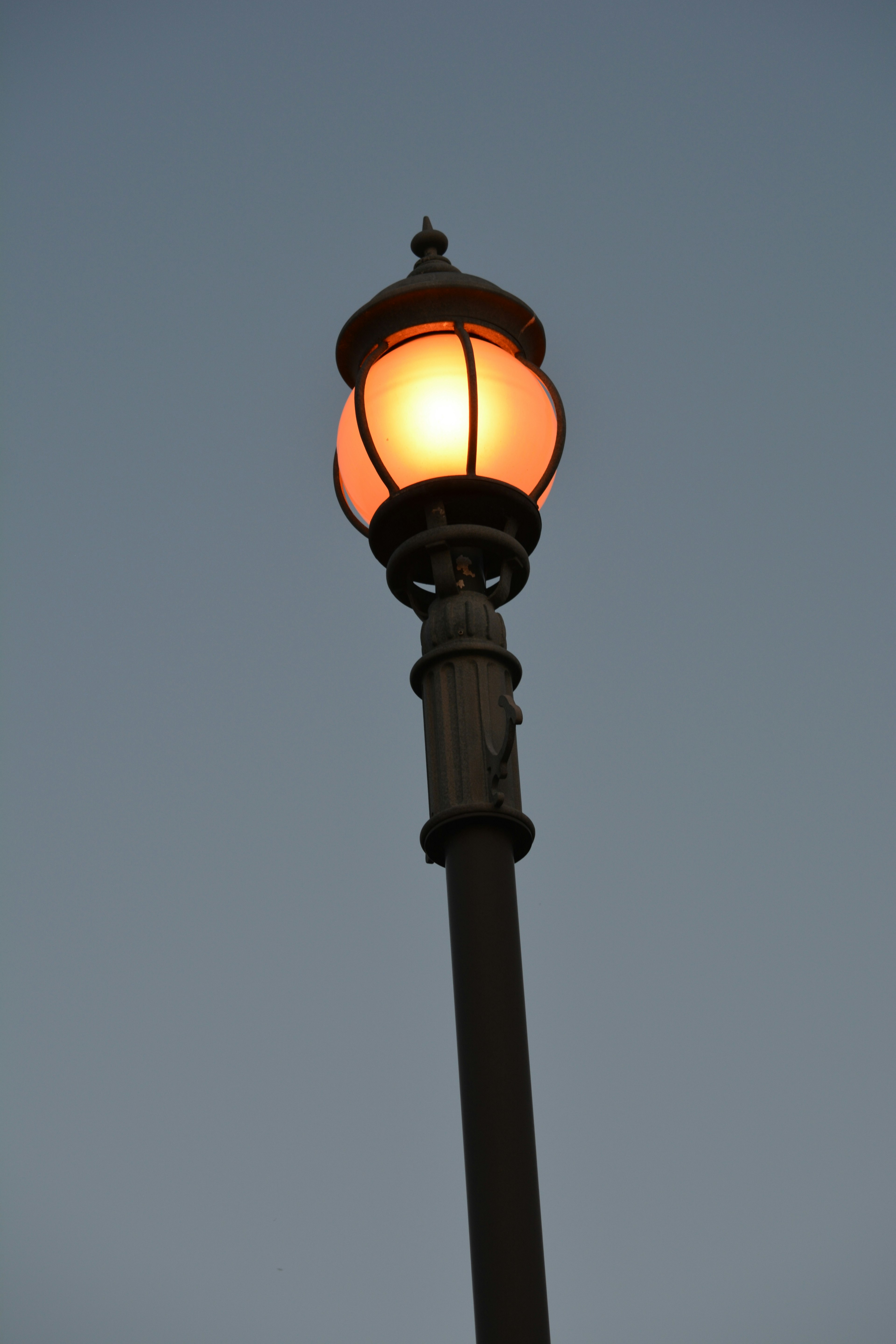 Farola emitiendo luz naranja al anochecer