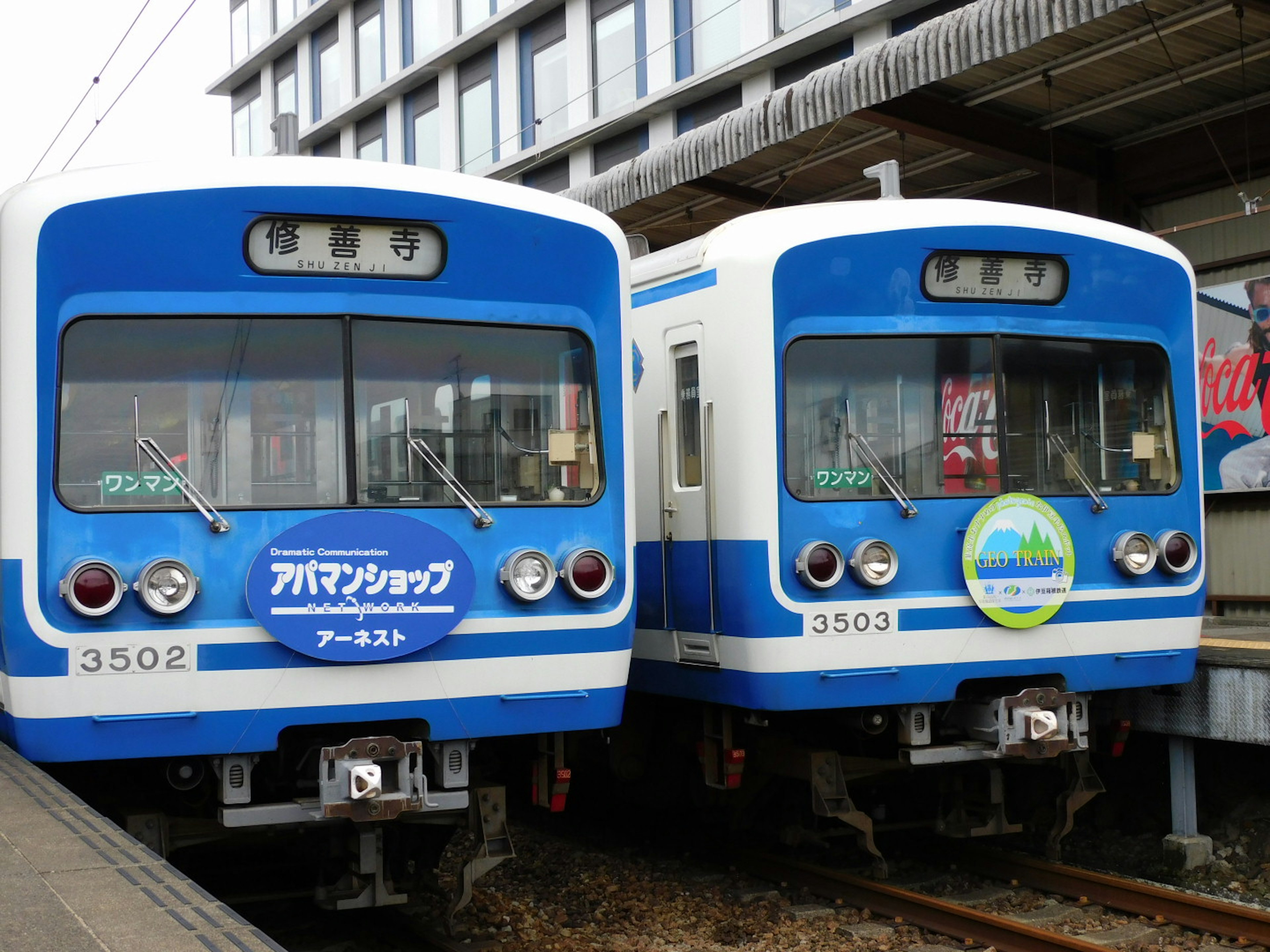 Dua kereta biru diparkir berdampingan di sebuah stasiun