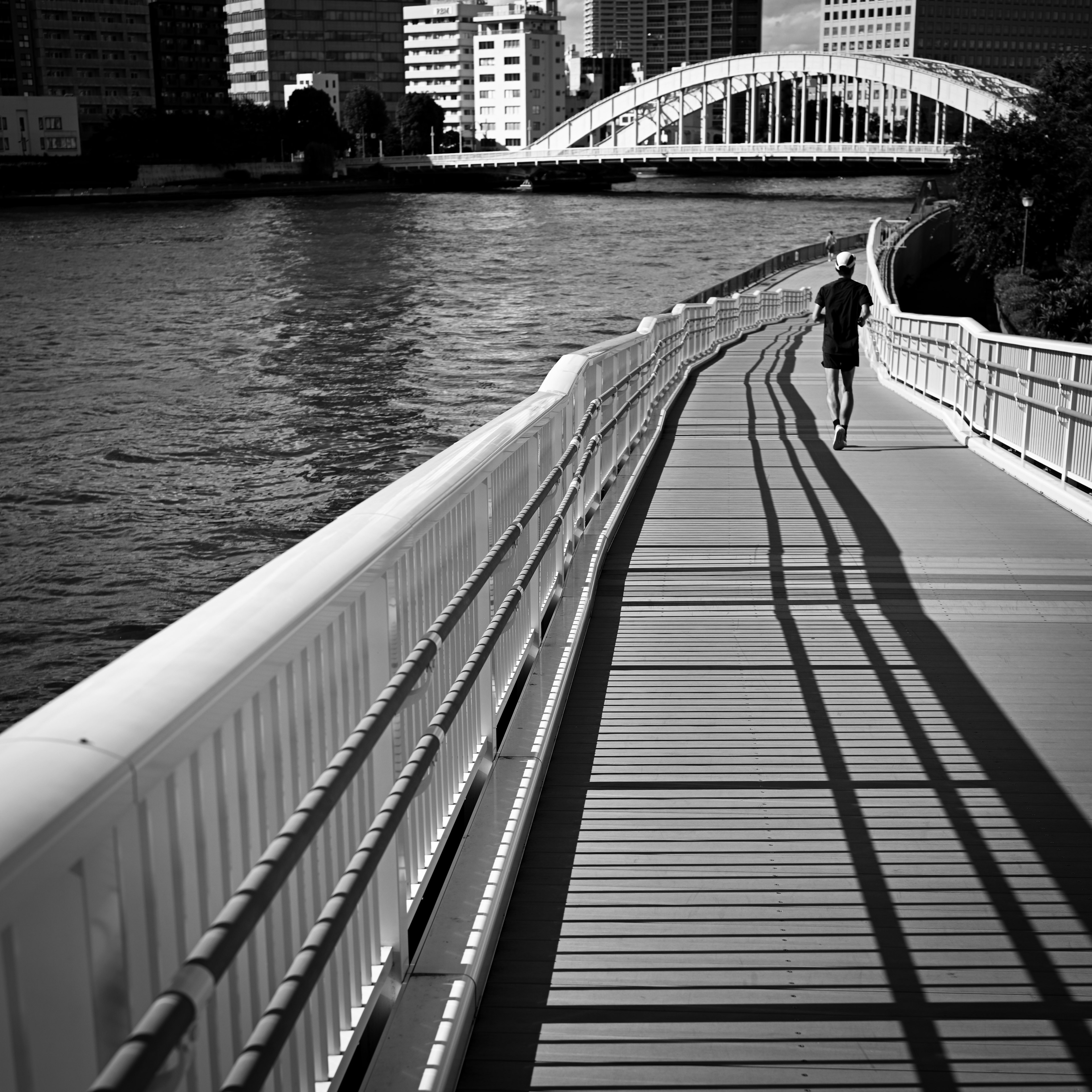 Silhouette of a person running on a riverside walkway with shadow patterns