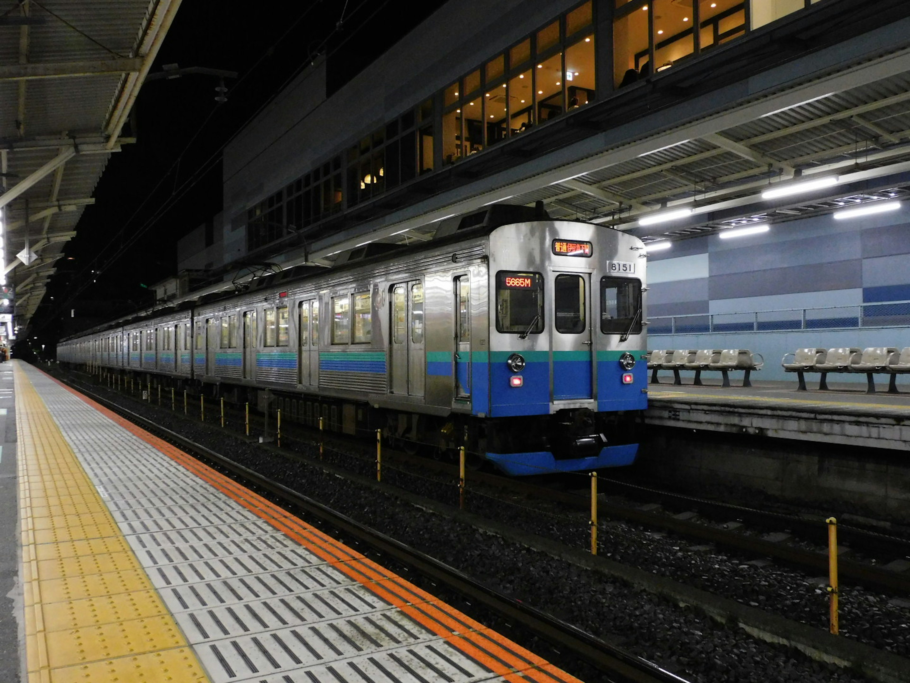 A blue and silver train stopped at a station at night