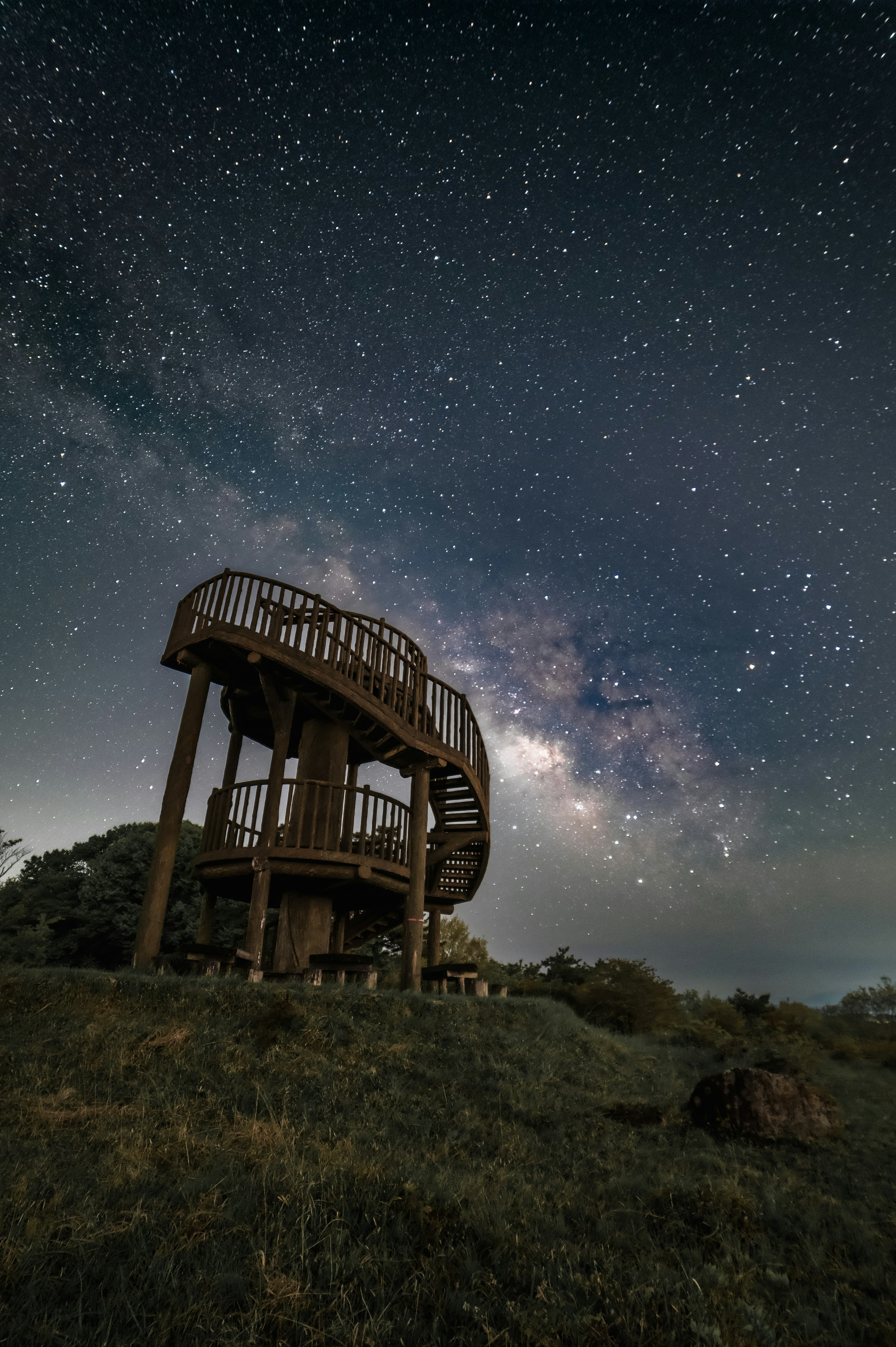 星空の下にある木製の展望台と満天の星々