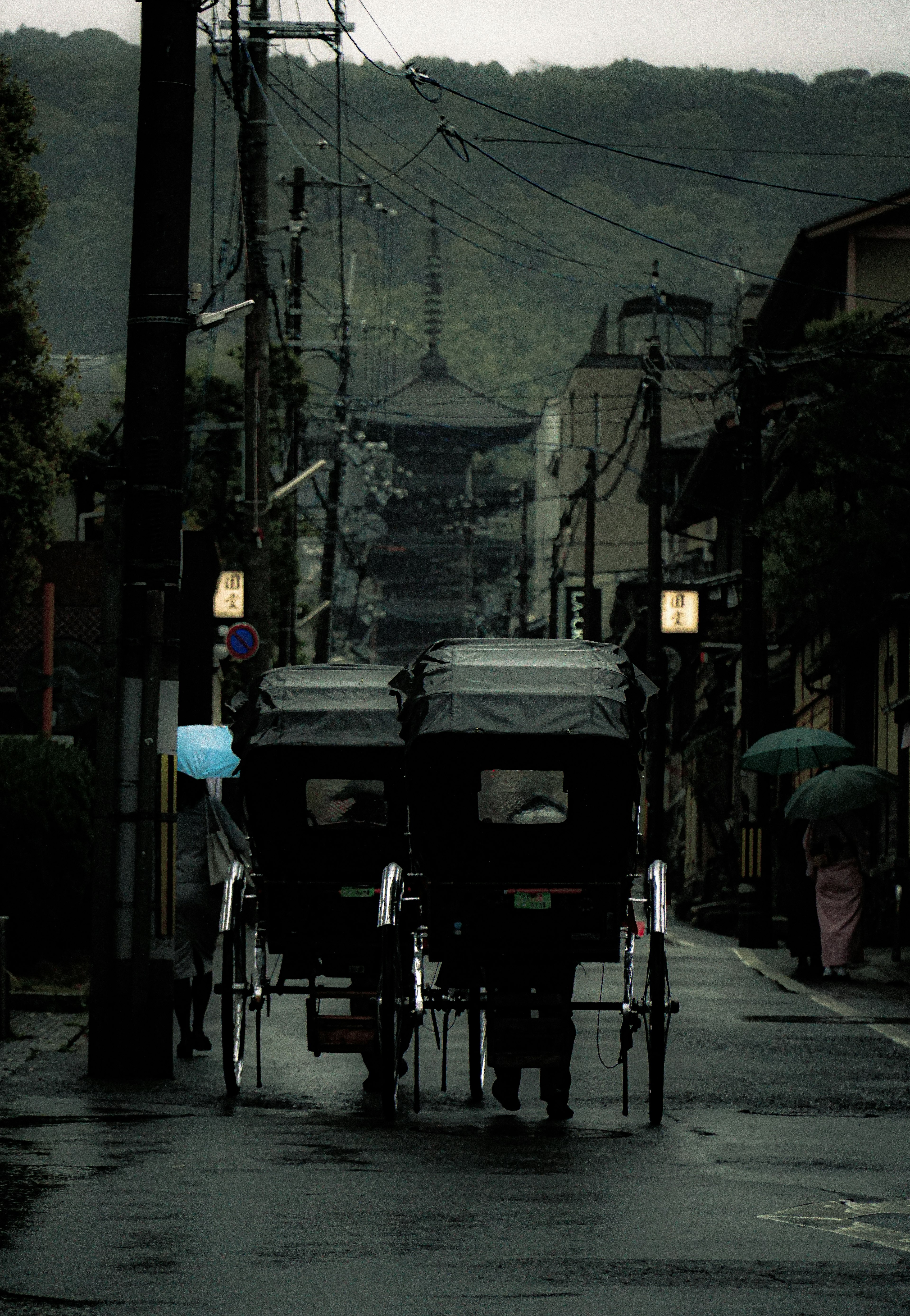 濡れた街路を走る人力車と古い建物の景色