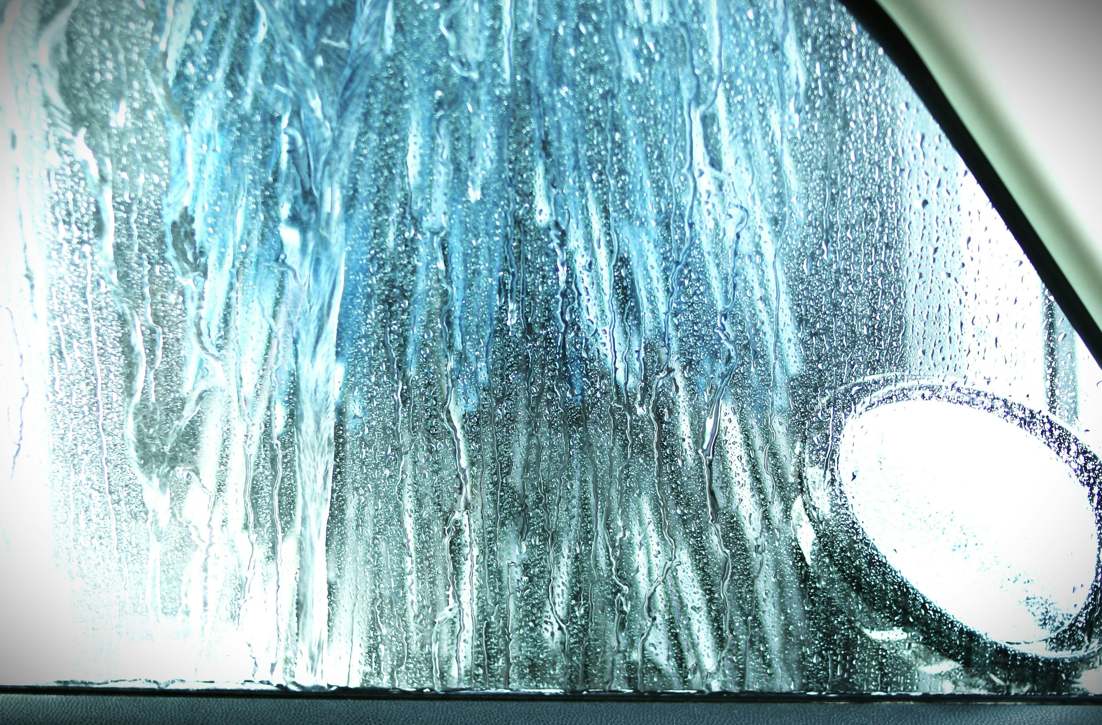 Water splashes and car wash brushes seen through a car window