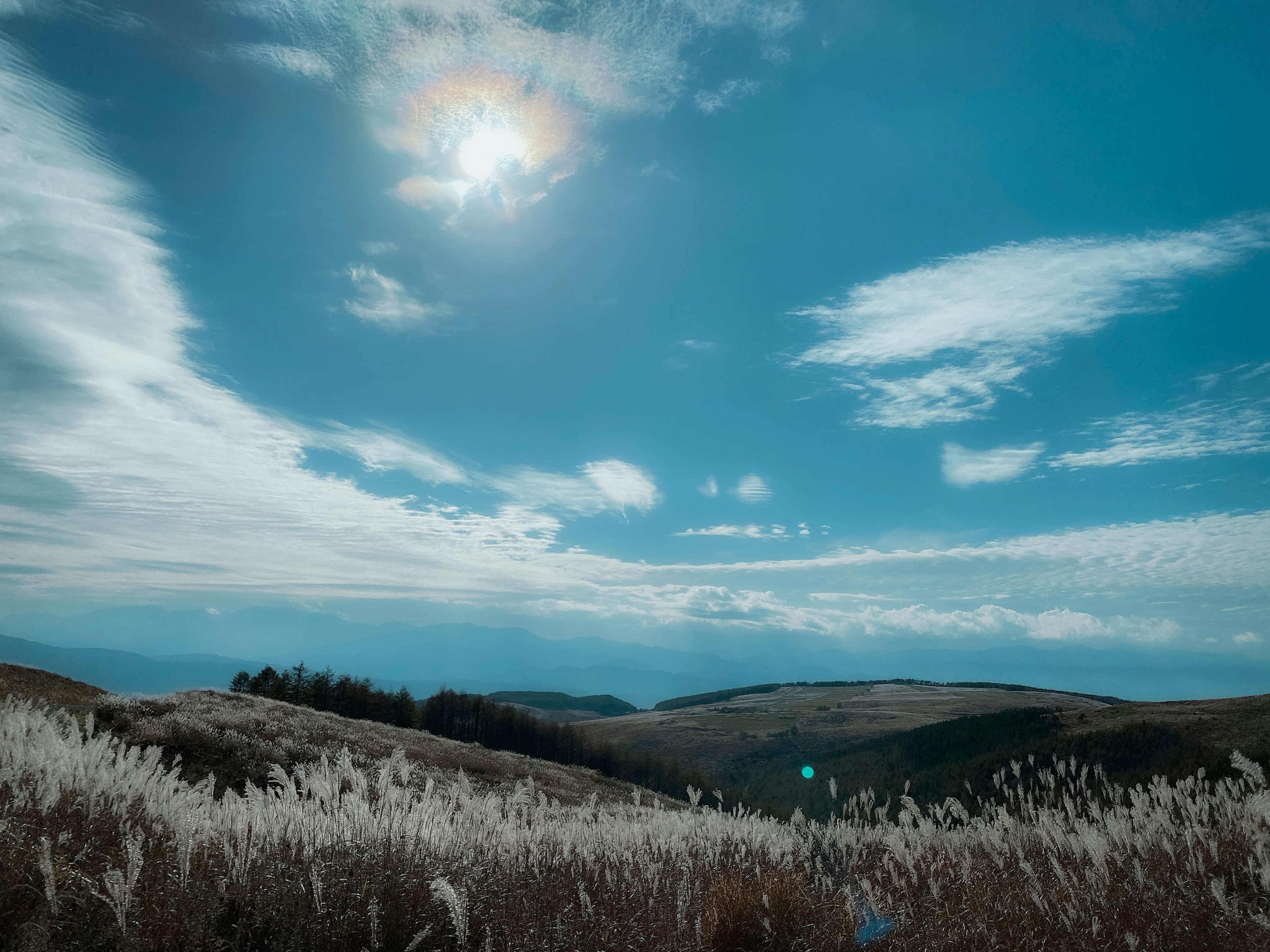 Landschaft mit hellem Sonnenschein in einem blauen Himmel mit Wolken über sanften Hügeln