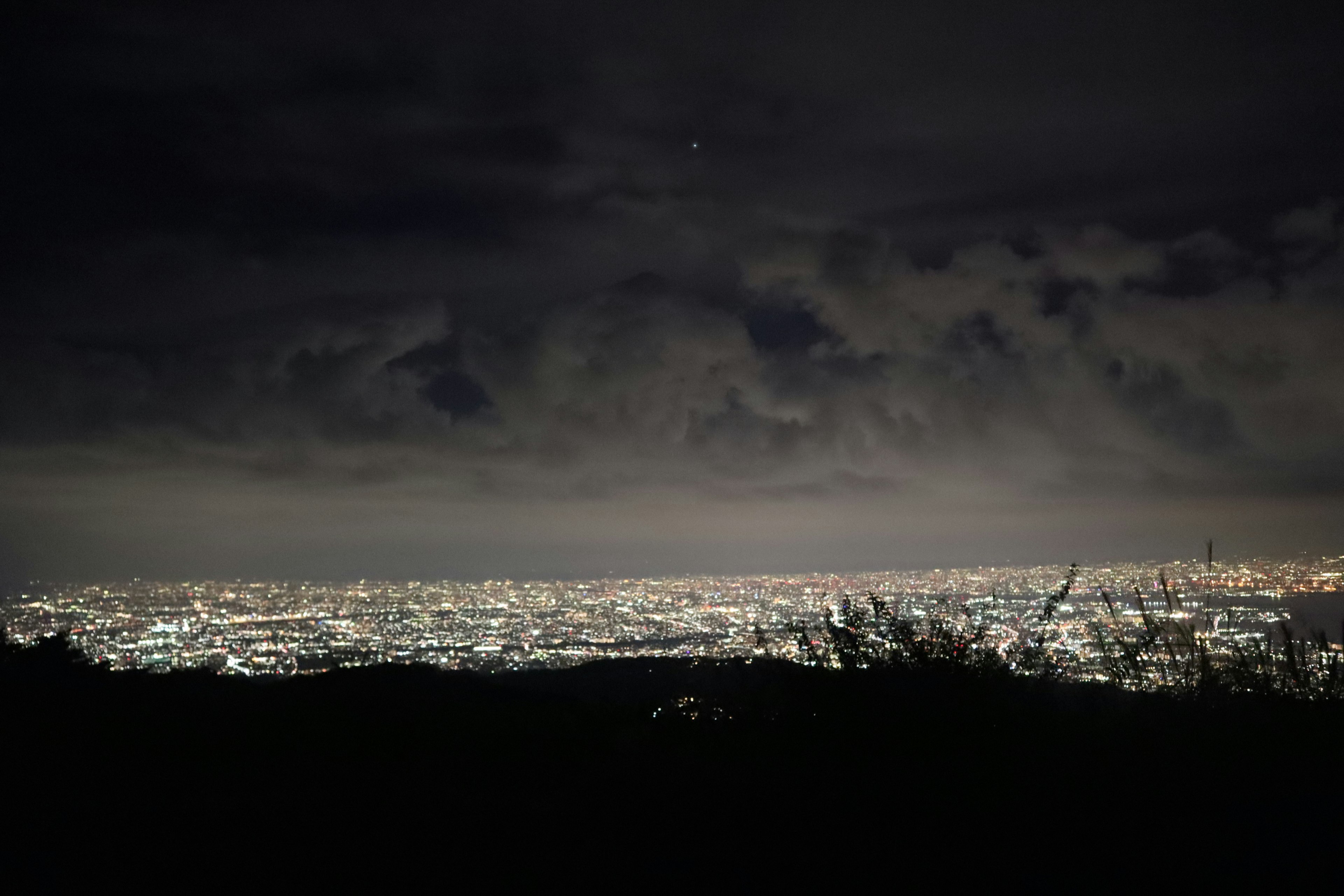 Paisaje urbano nocturno con luces de la ciudad y cielo nublado