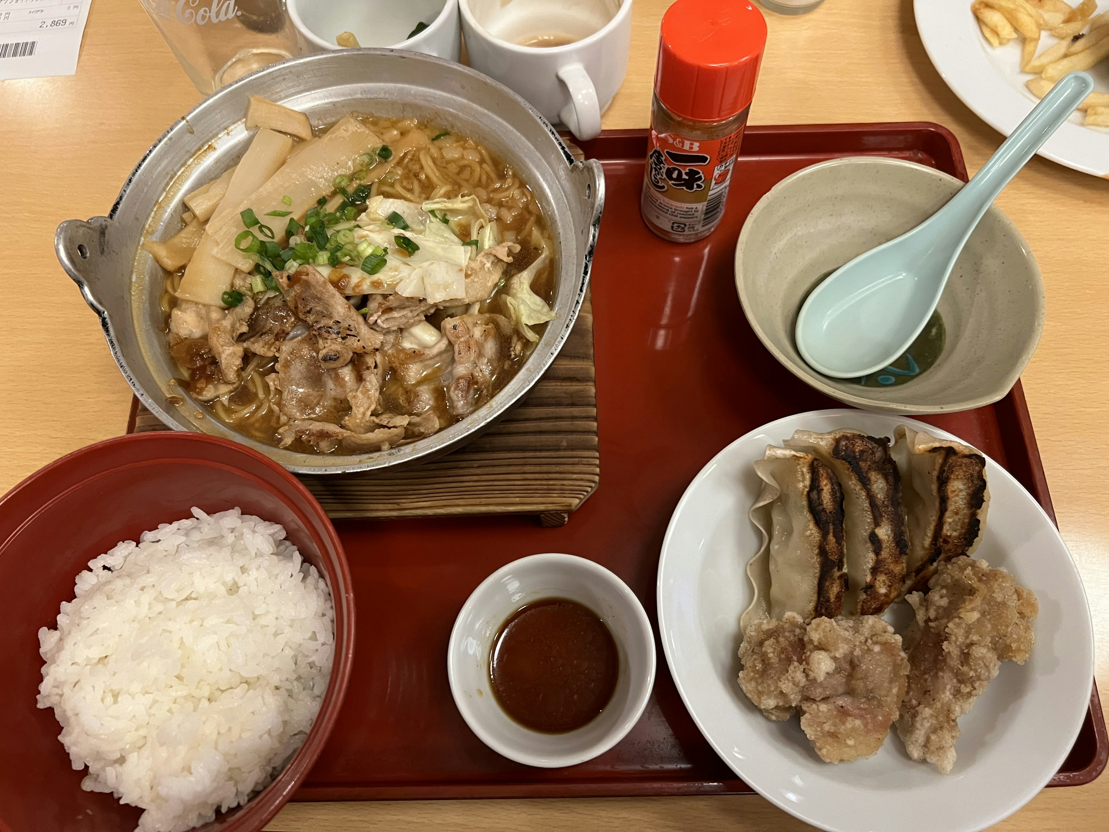 温かい鍋料理とご飯のセット、肉と野菜、調味料が添えられた食事