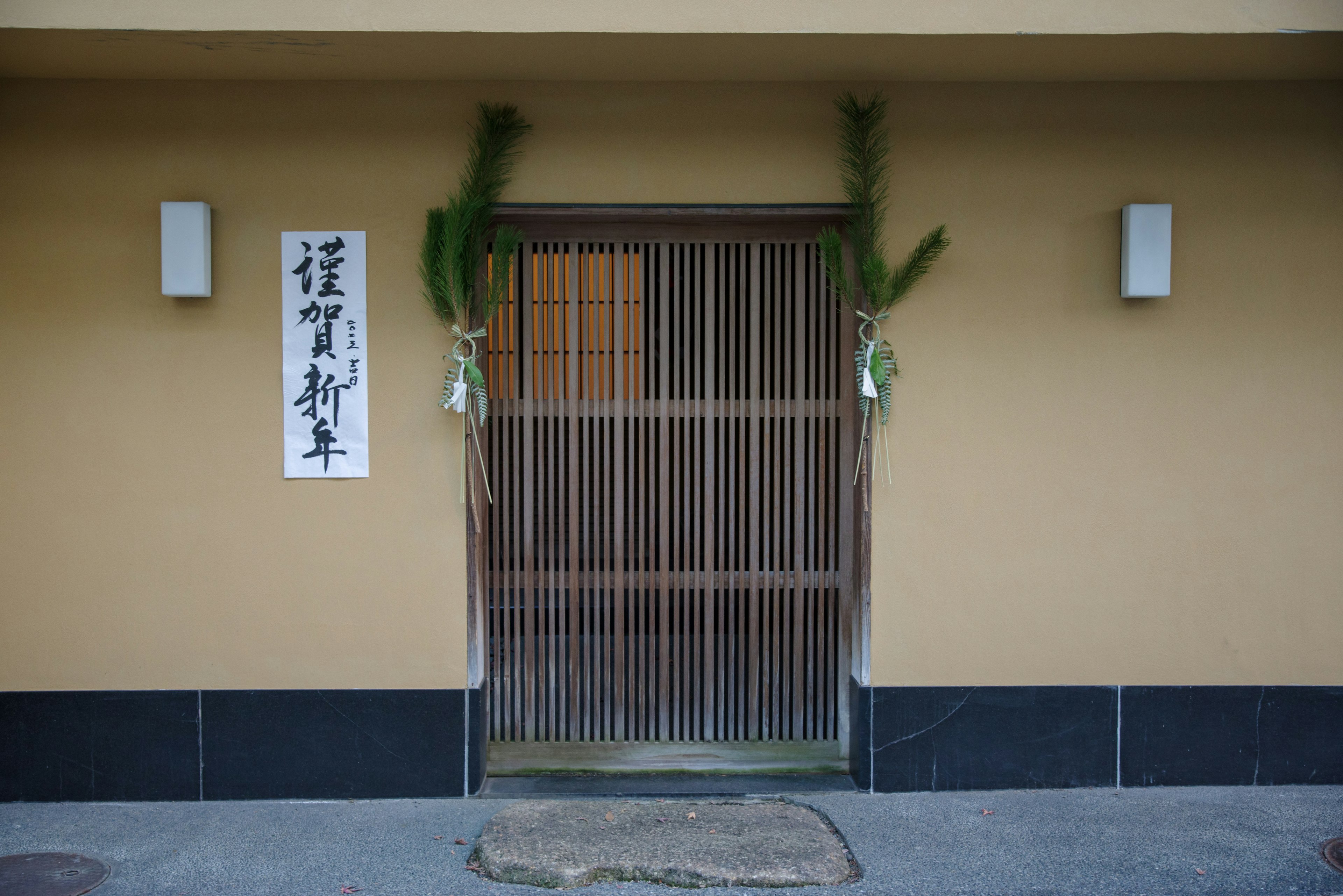 Eingang eines traditionellen japanischen Hauses mit Lamellentür und Pinienverzierungen