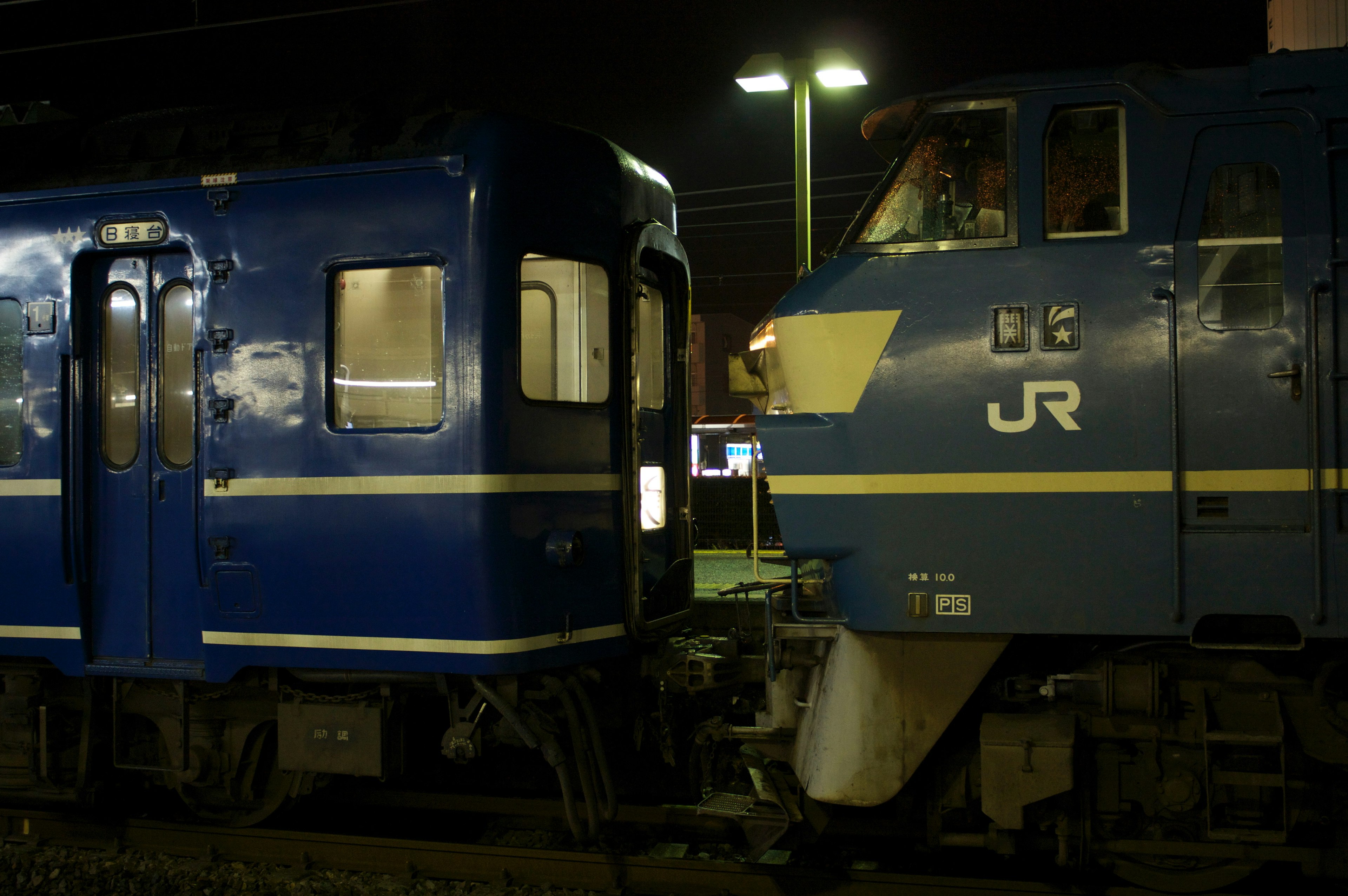 Tren azul y locomotora detenidos en estación nocturna