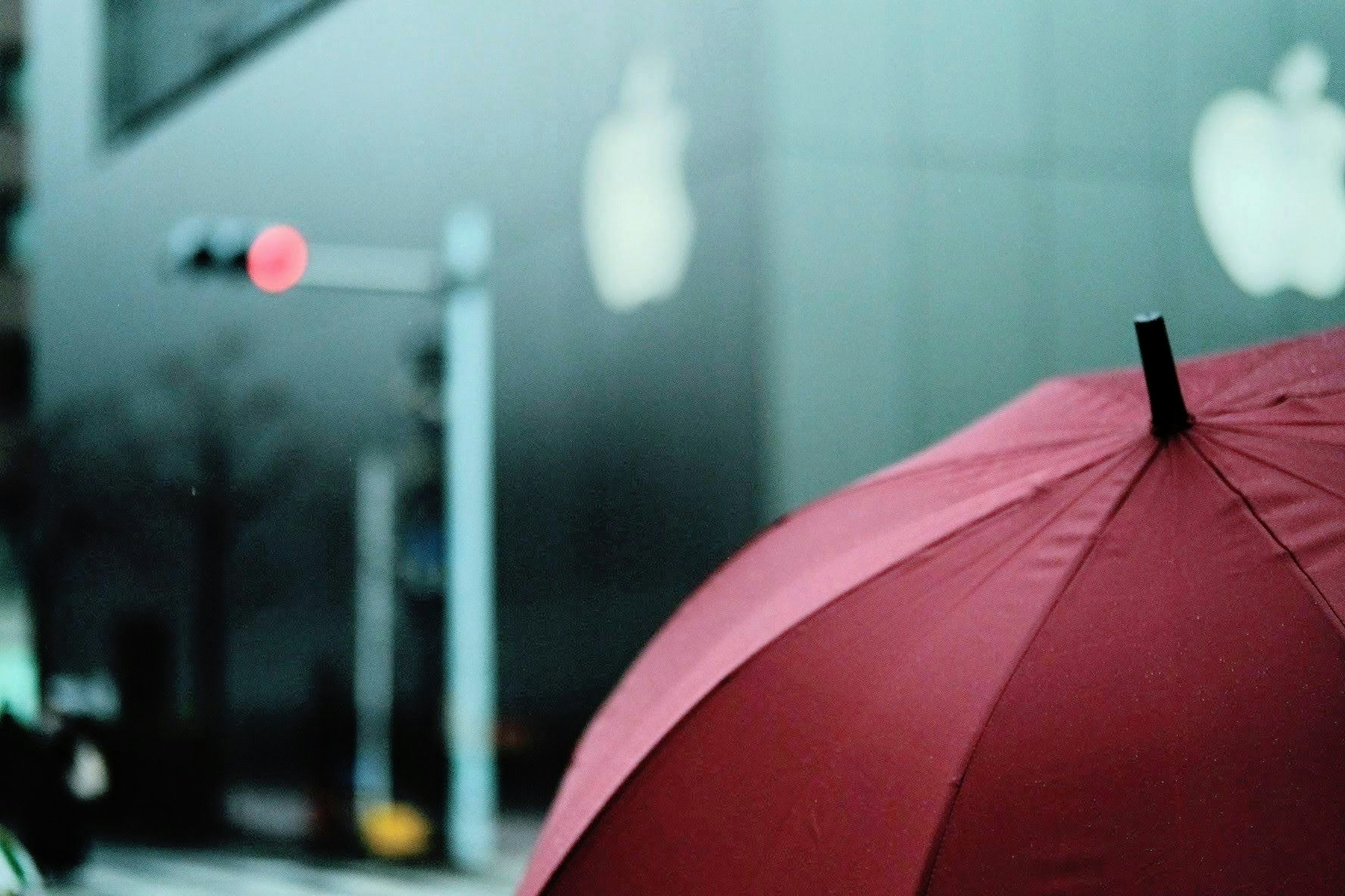 Roter Regenschirm mit Apple-Logos im Hintergrund auf einer Stadtstraße