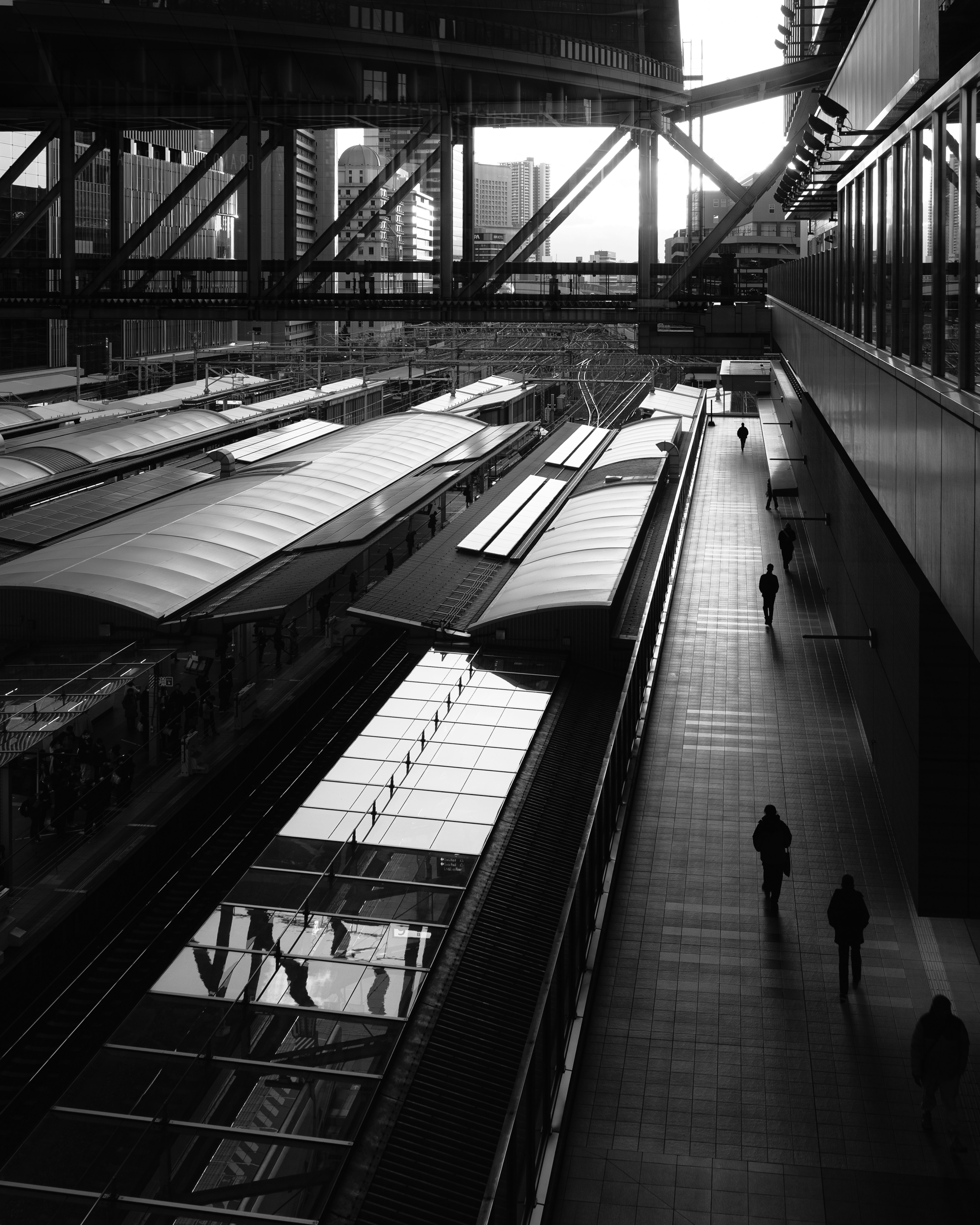 Scena di stazione ferroviaria in bianco e nero con banchine e figure in silhouette