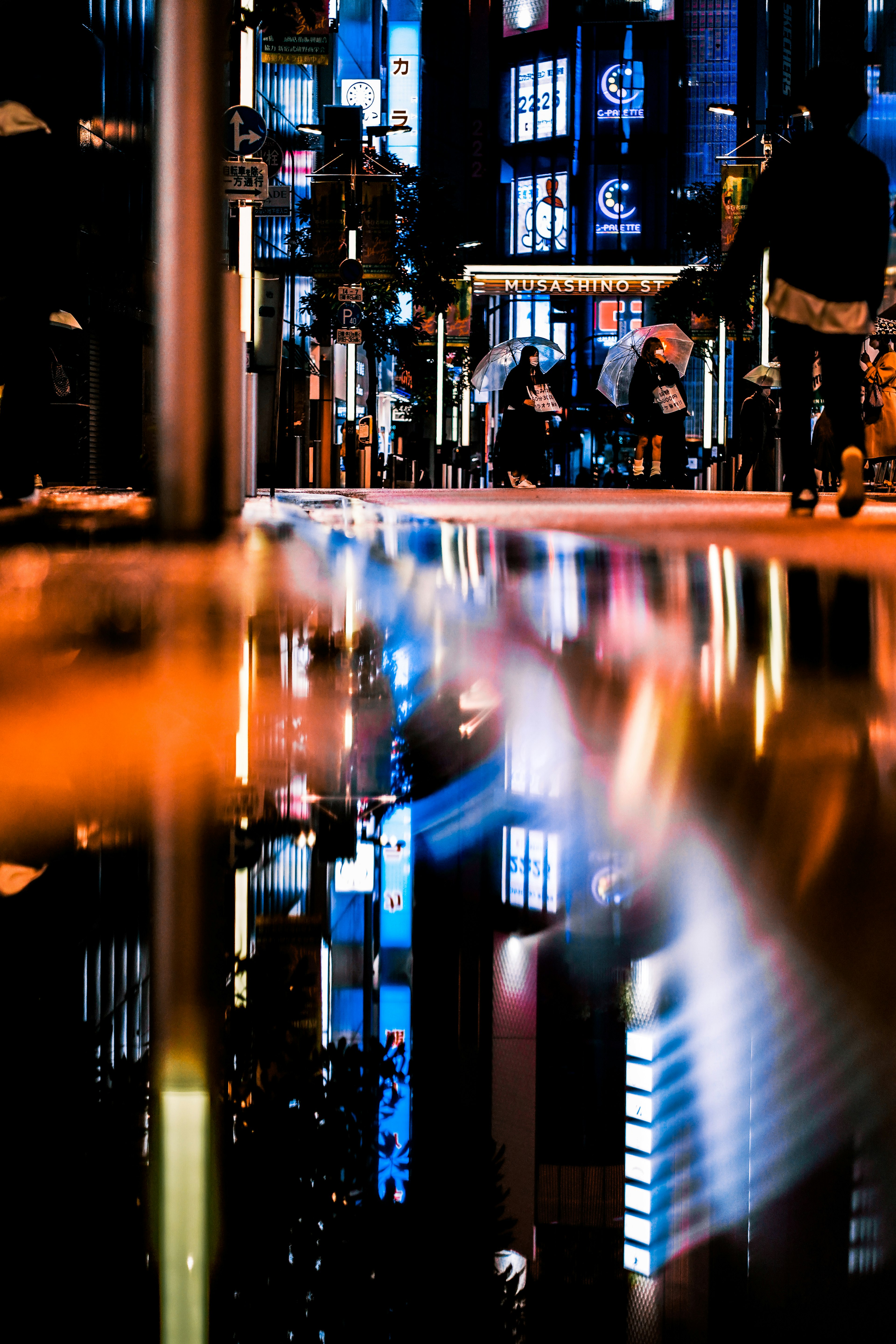 Reflet des lumières néon sur une rue urbaine mouillée la nuit