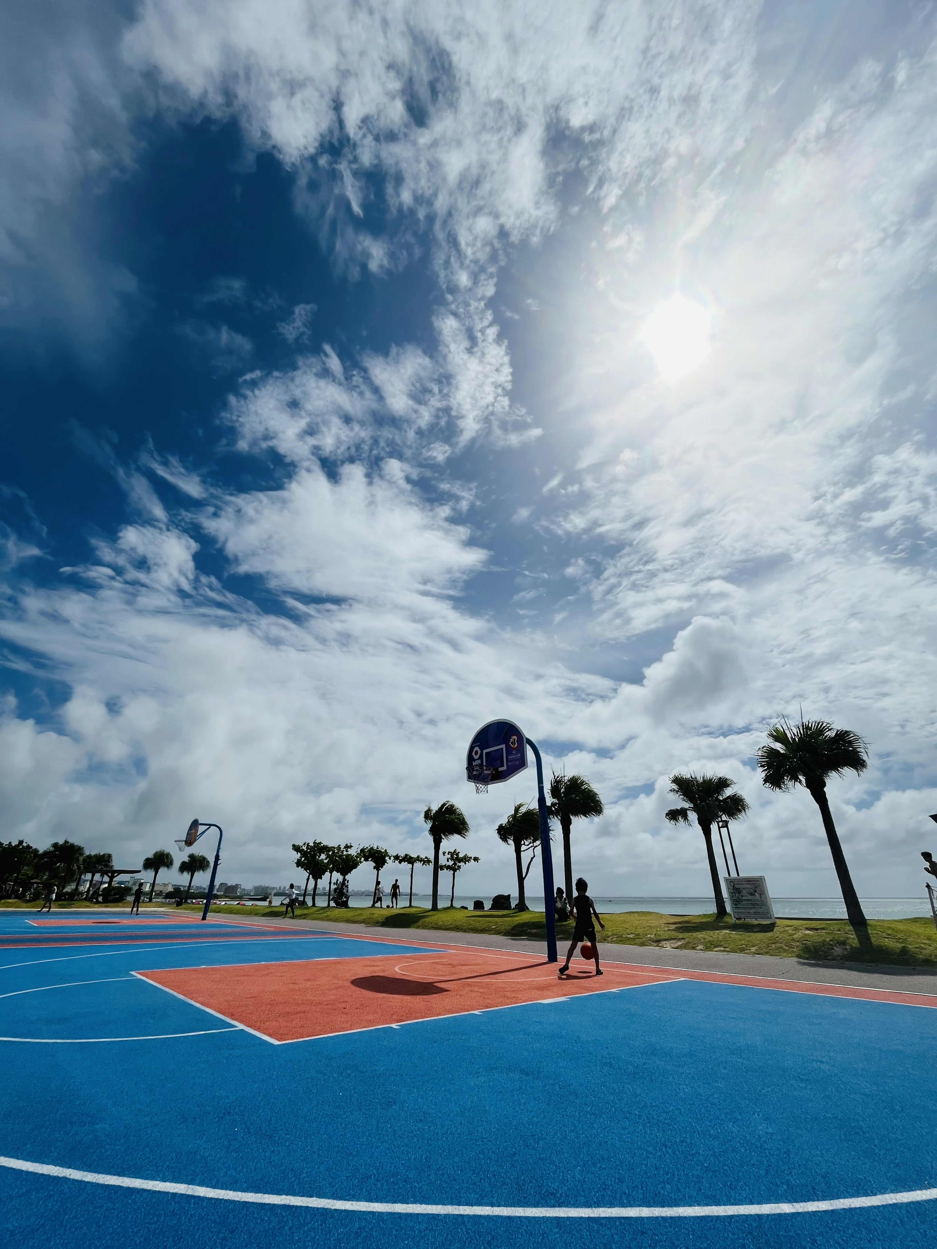 Terrain de basket-ball bleu vif sous un ciel partiellement nuageux