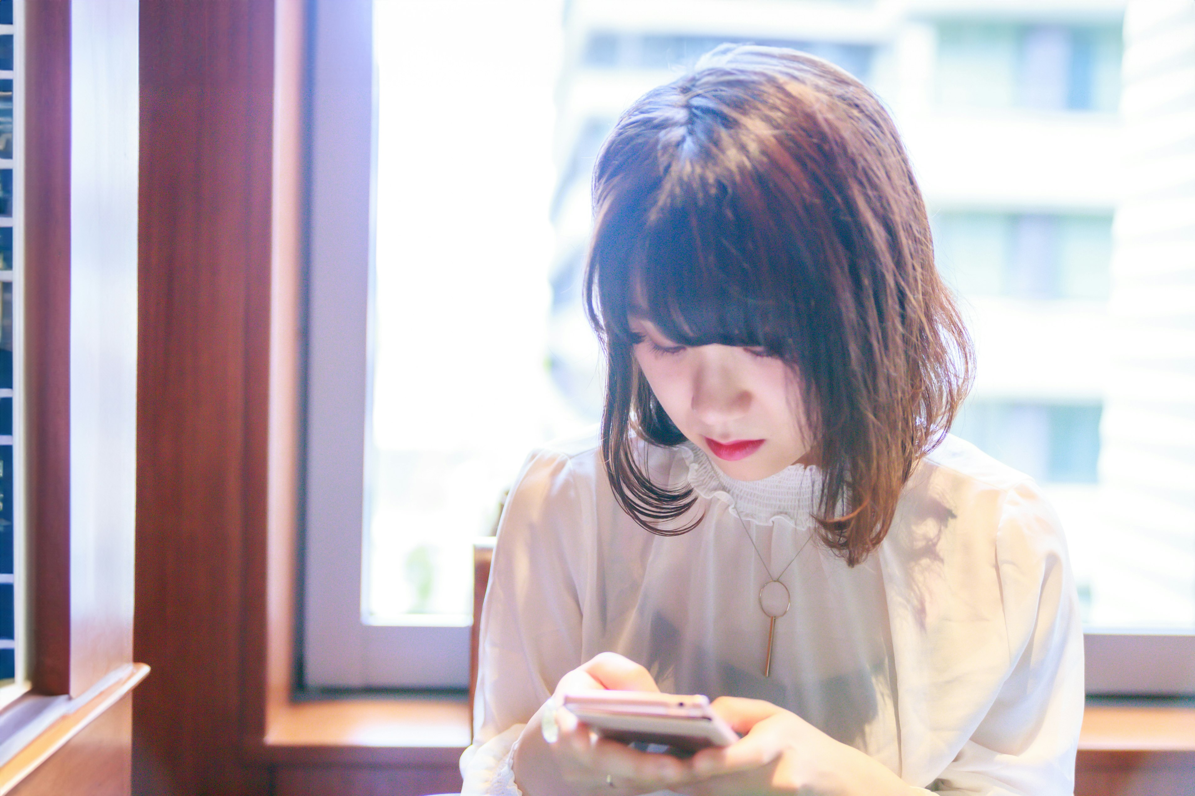 A woman using a smartphone near a window