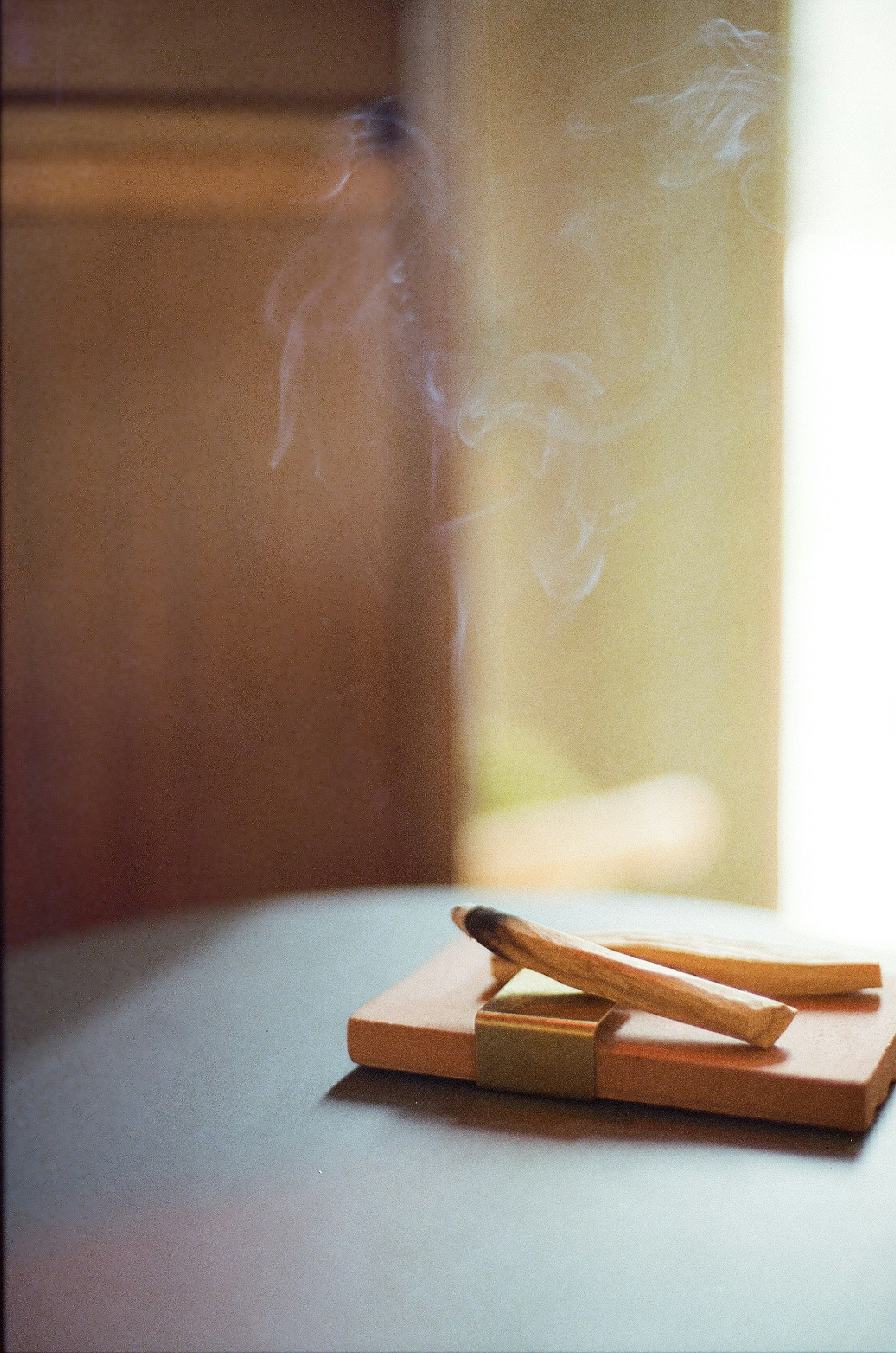 Bastones de incienso emitiendo humo en un soporte de madera con luz suave