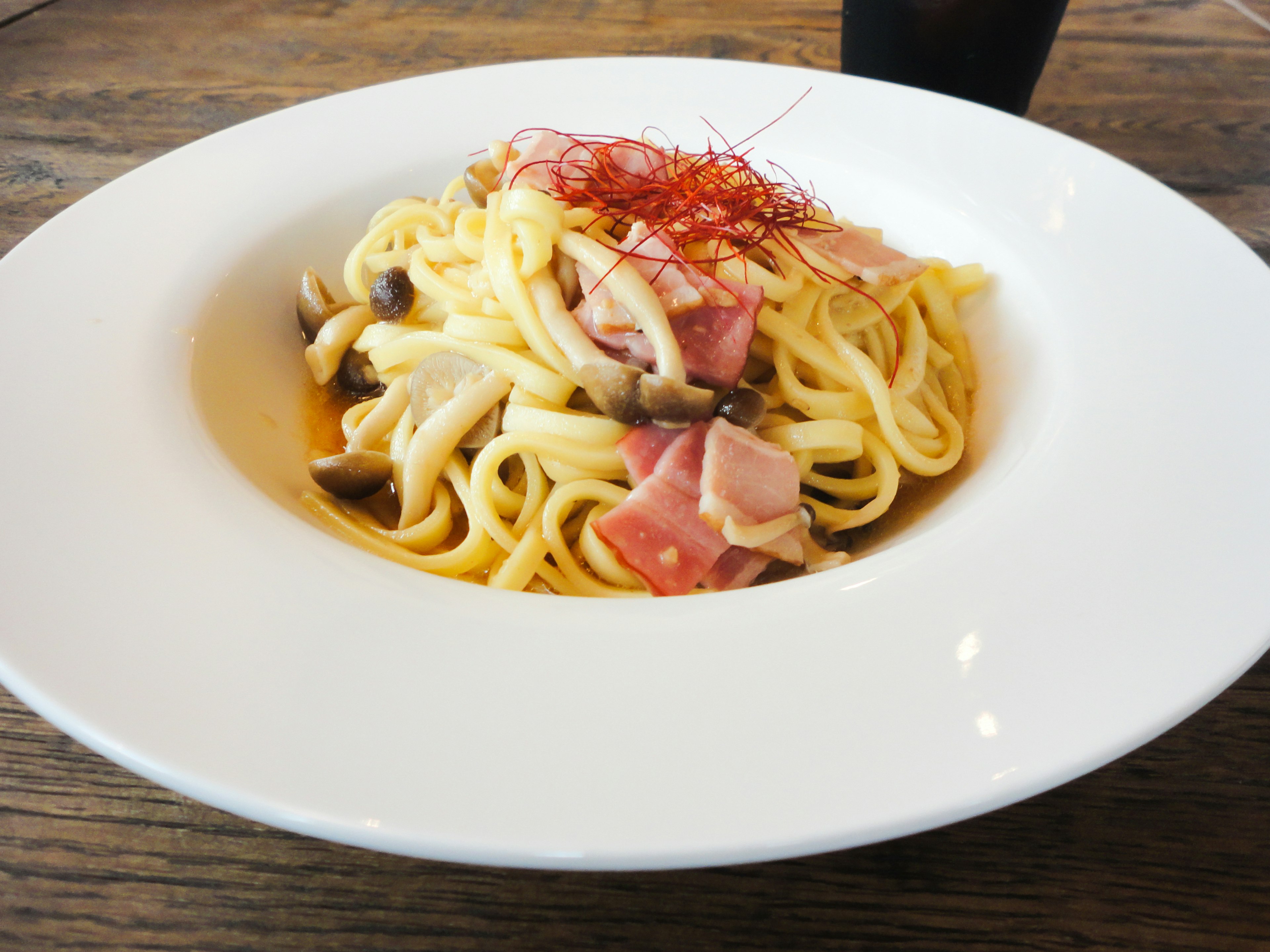 Plate of pasta topped with ham and mushrooms