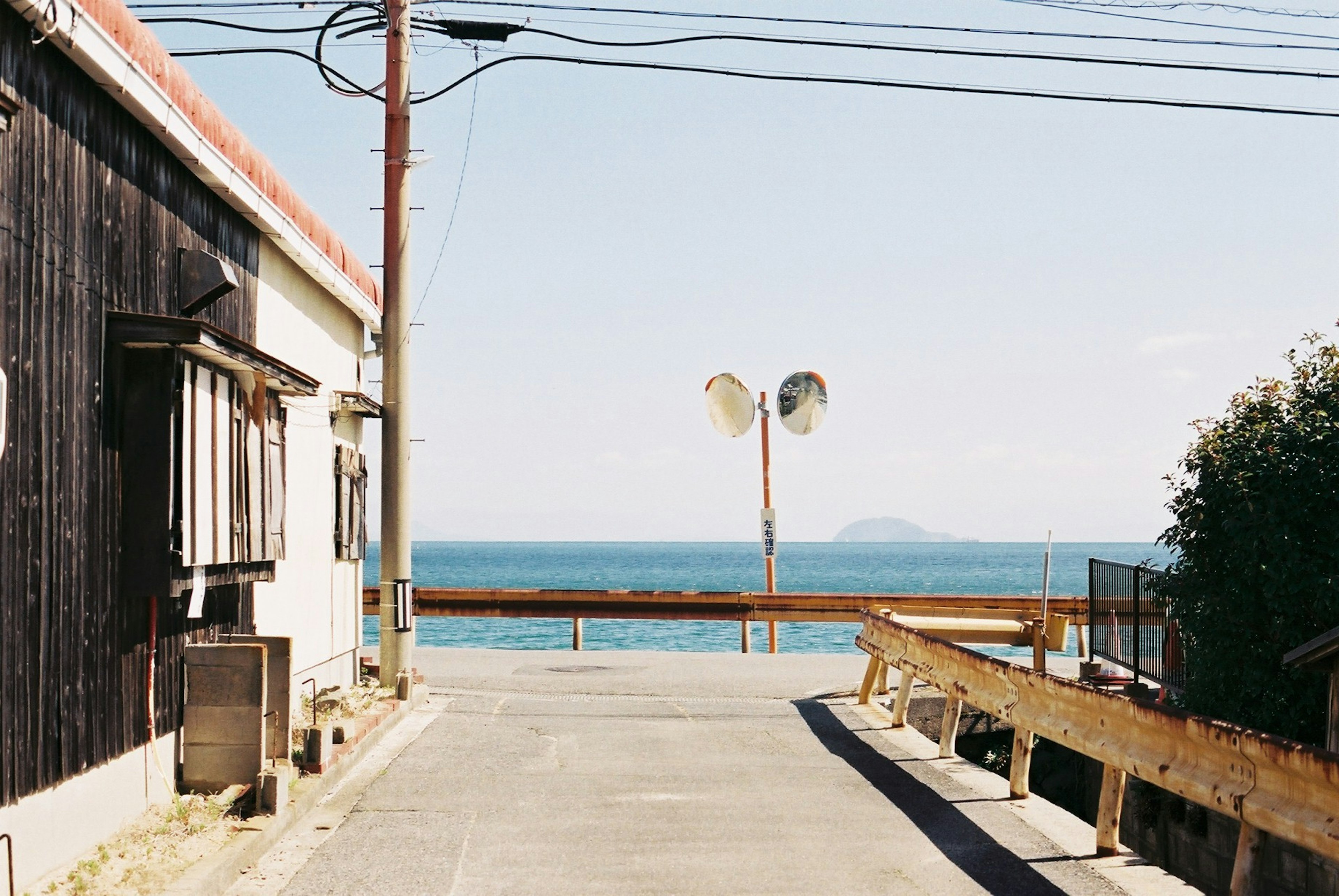 A quiet street view overlooking the sea with an old house and utility poles