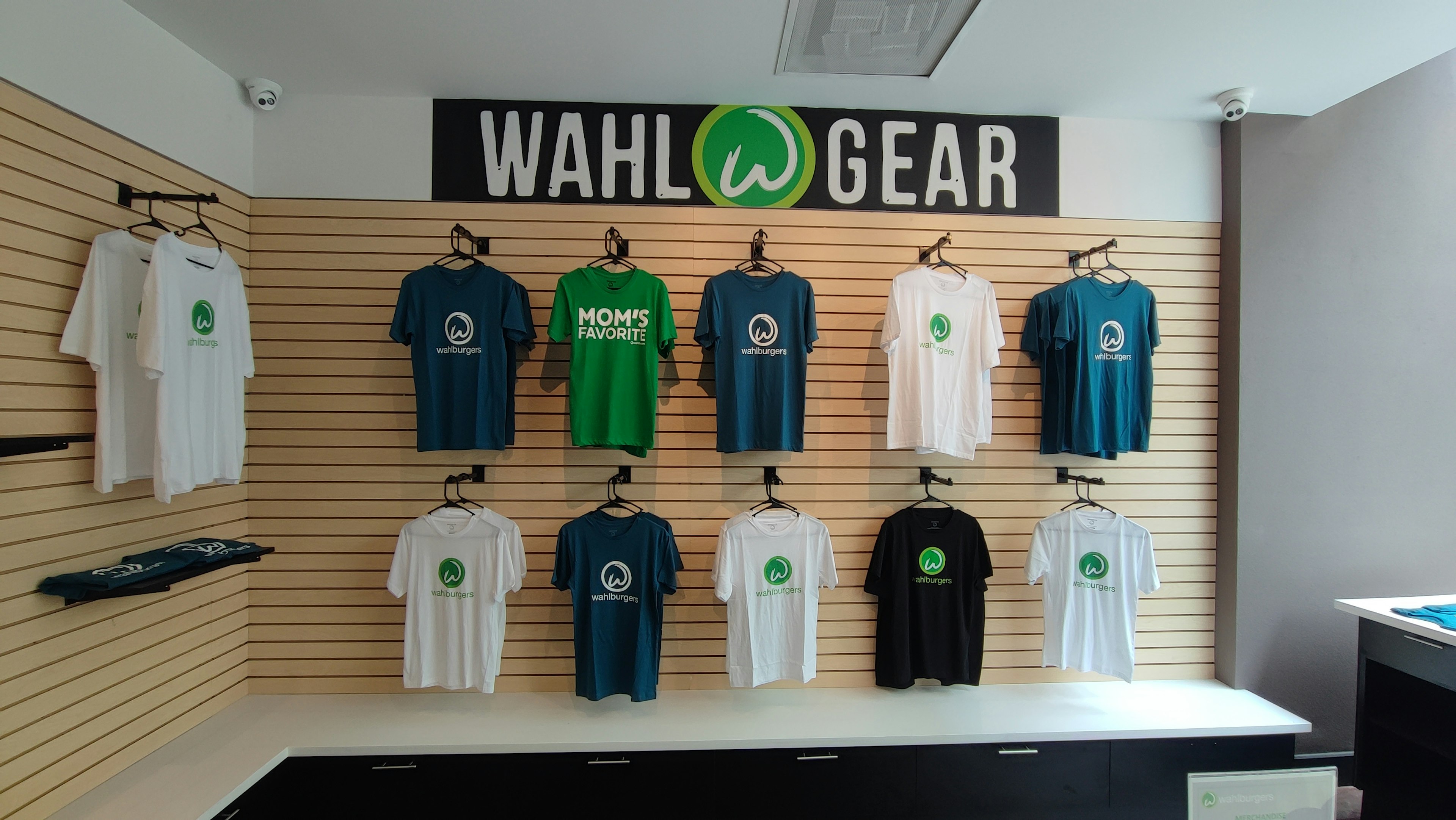 Esposizione di magliette Wahl Gear di vari colori su una parete