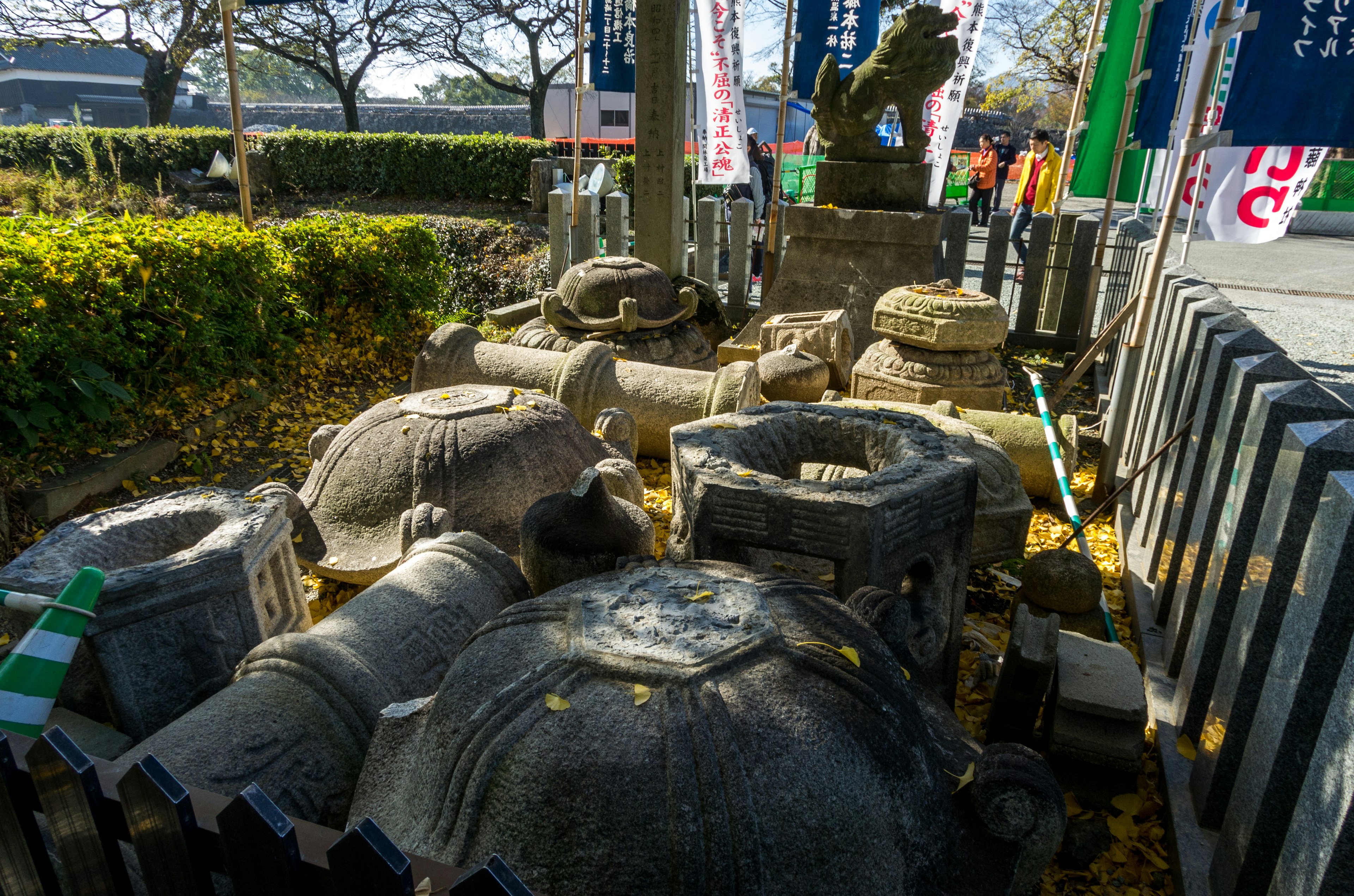 View of old stone sculptures arranged with green plants and flags in the background