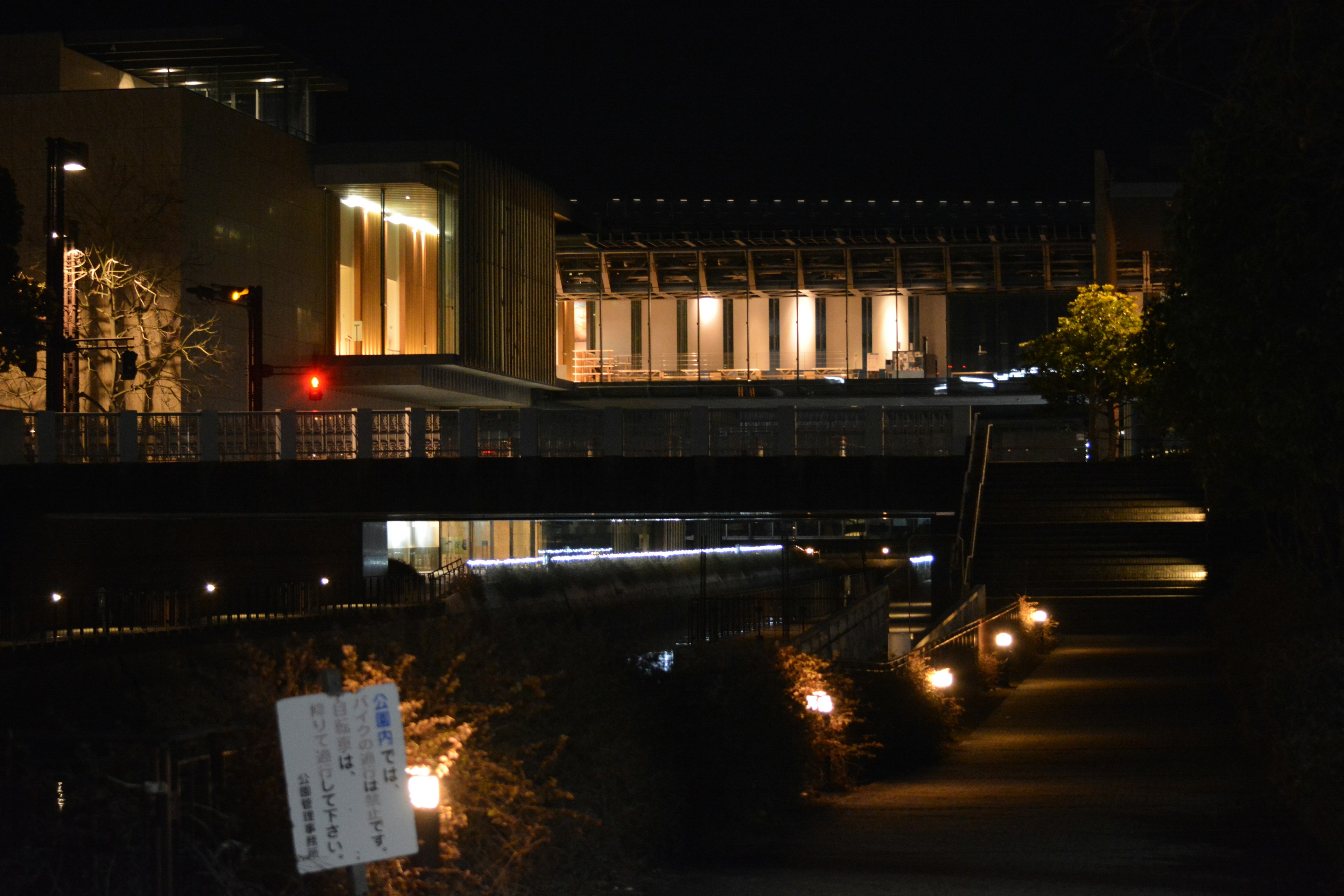 夜間城市景觀，燈光照亮建築和小道，附近有橋和綠化