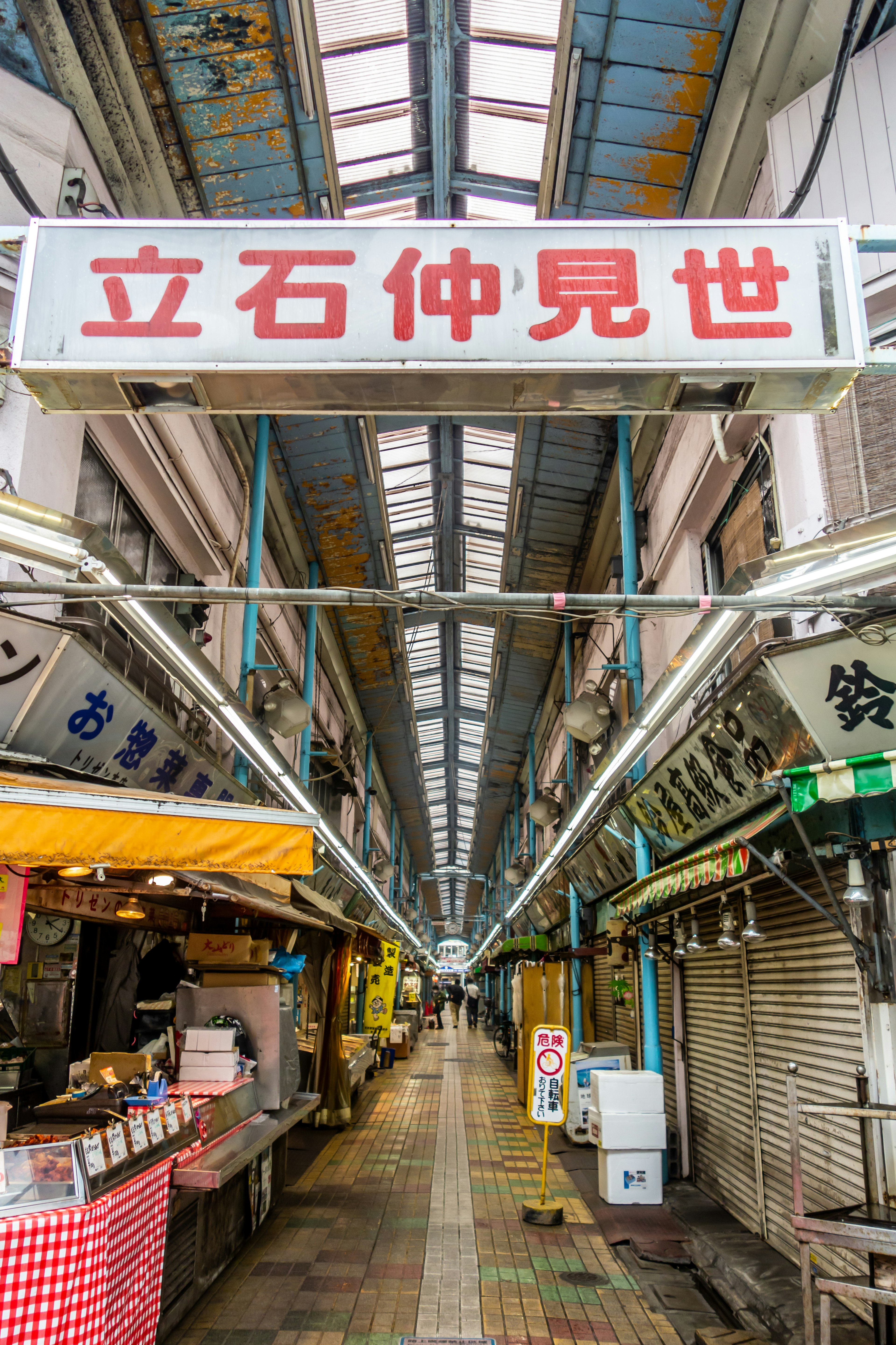 A view of a market street with a large sign and stalls