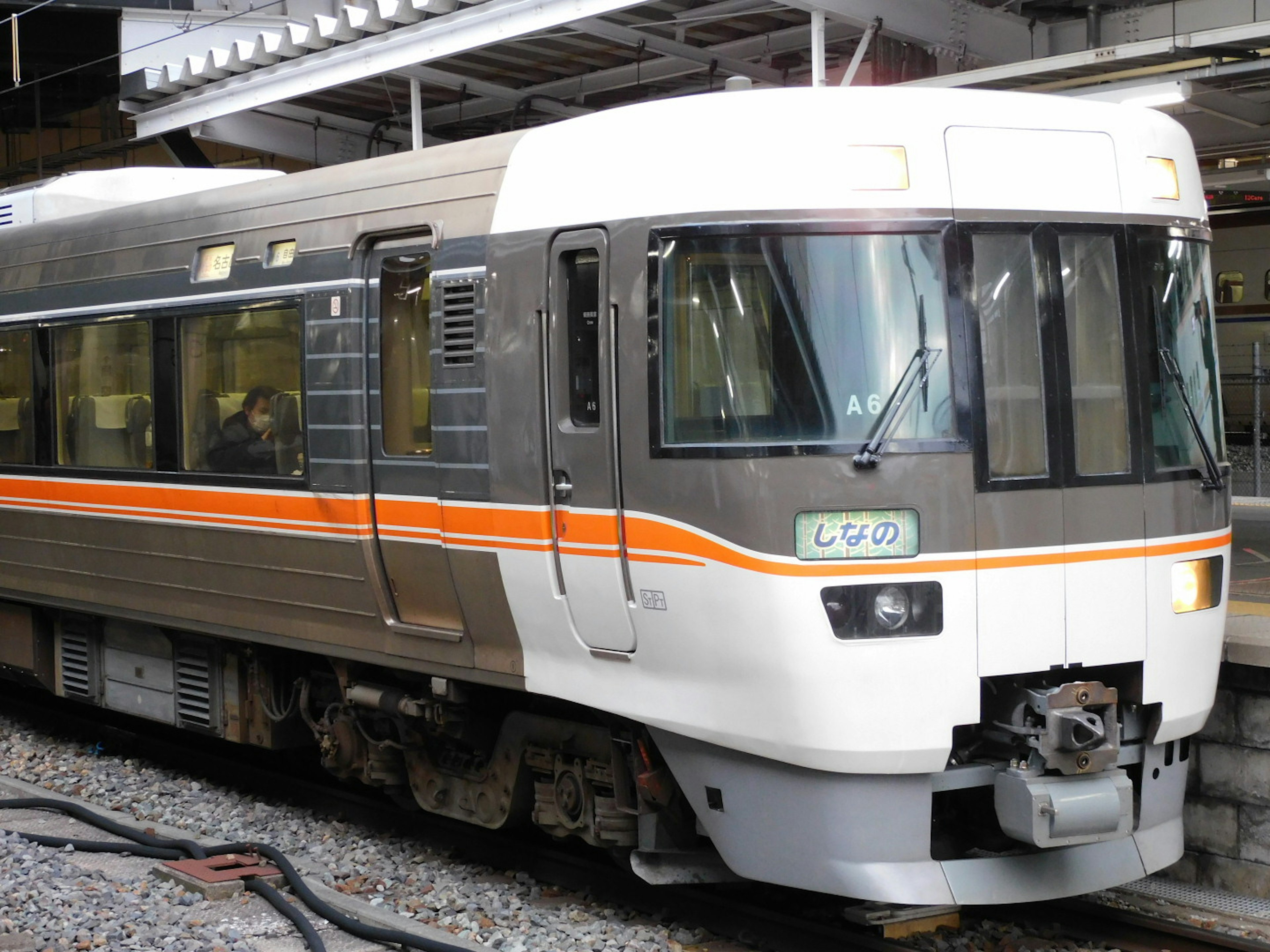 Japanese train with orange stripe parked at a station