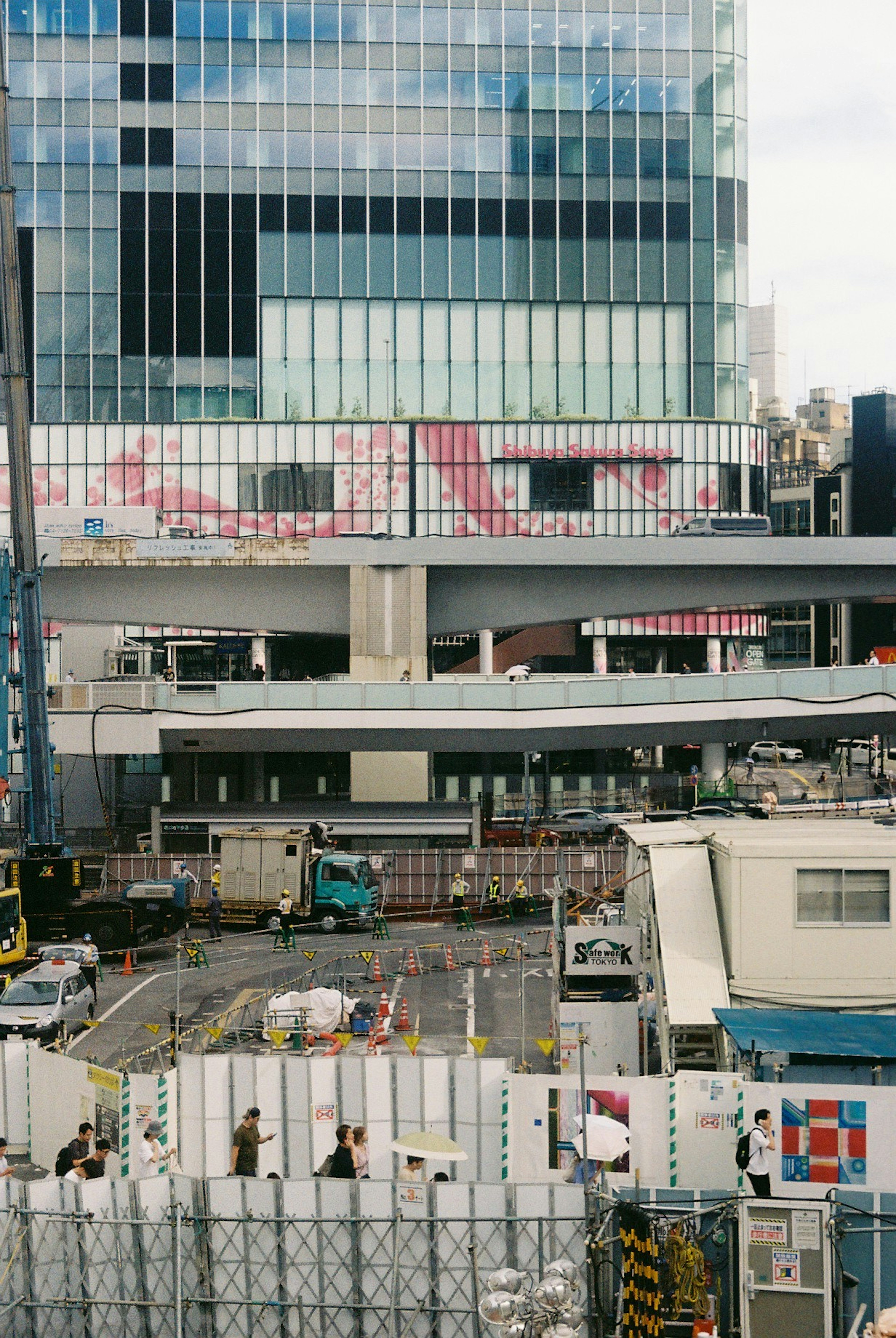 Imagen que muestra trabajos de construcción en curso frente a un rascacielos con barreras de construcción y maquinaria en las cercanías