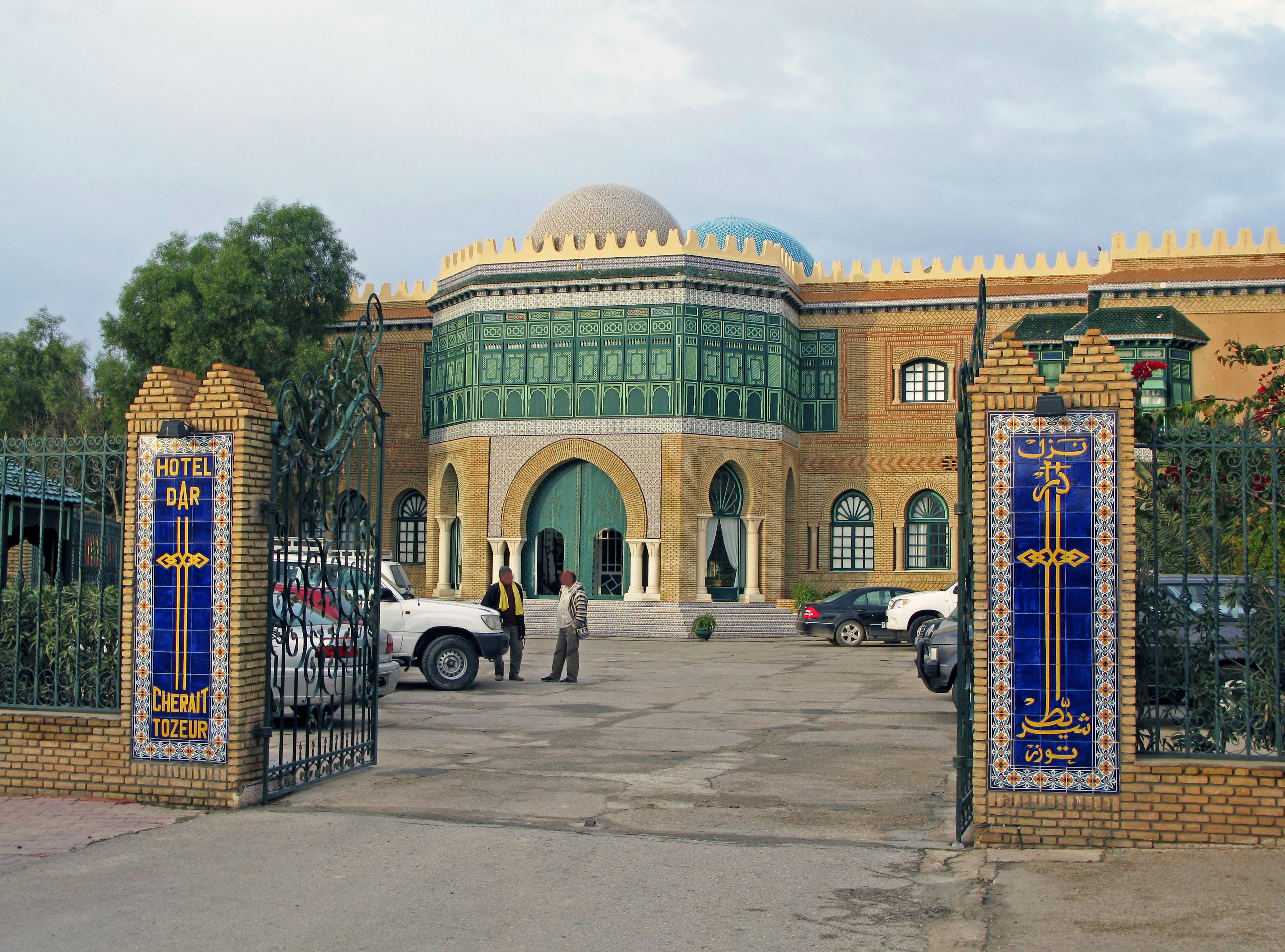 Impresionante fachada de edificio de estilo mezquita con azulejos decorativos y cúpula, entrada con puerta de hierro forjado