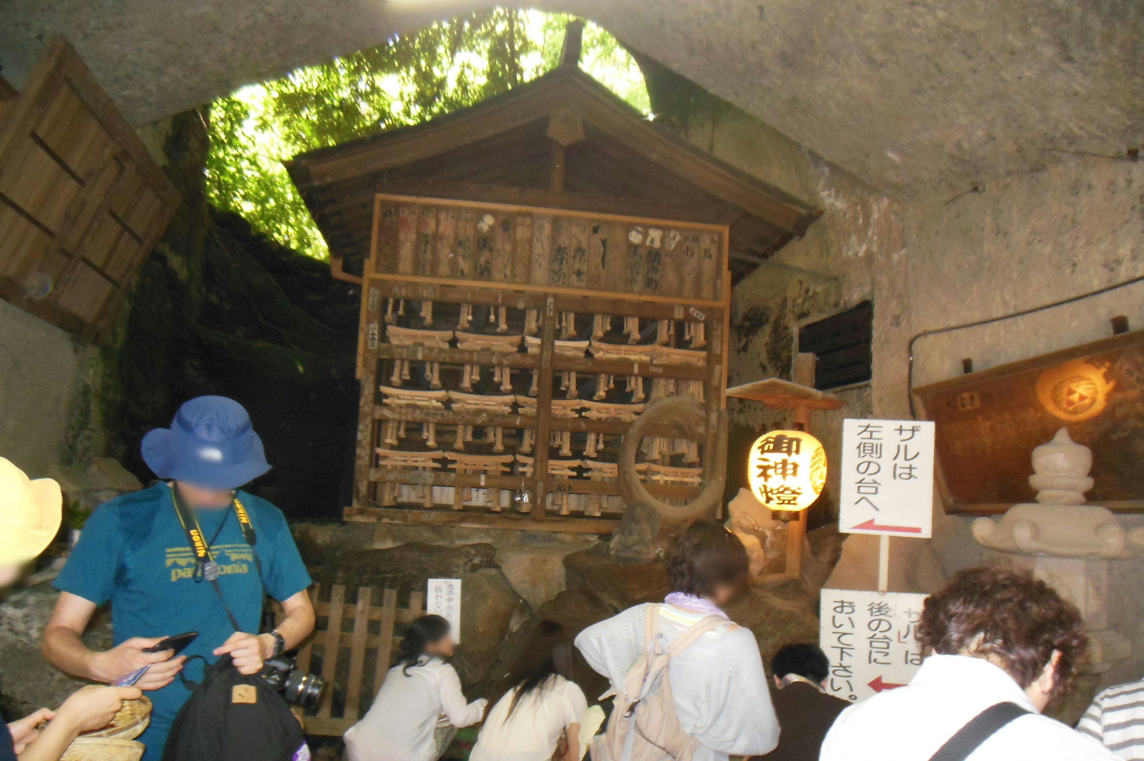 Étagère en bois avec de petites statues à l'intérieur d'une grotte avec des touristes