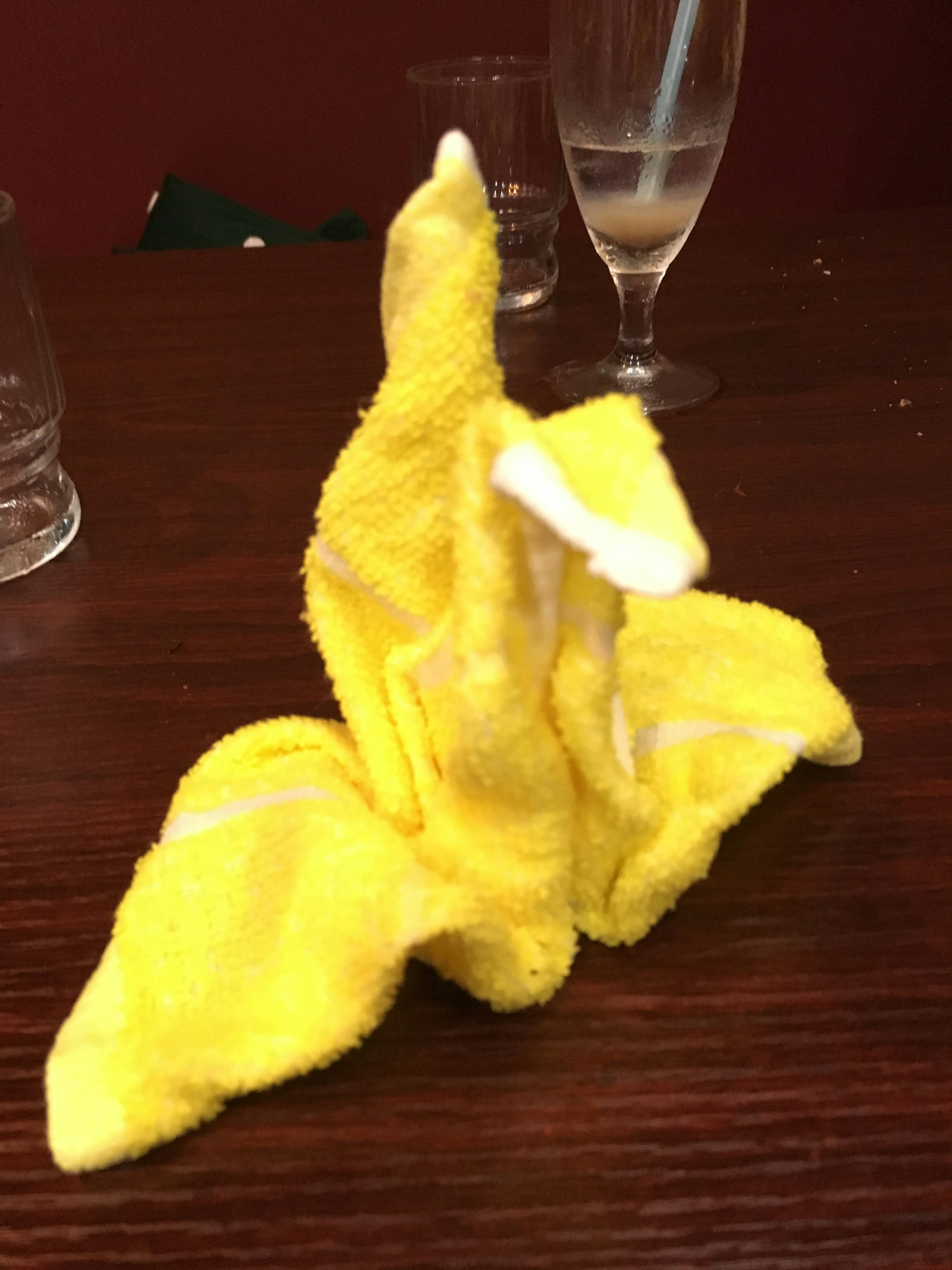 A towel sculpture shaped like a banana made from yellow fabric placed on a table