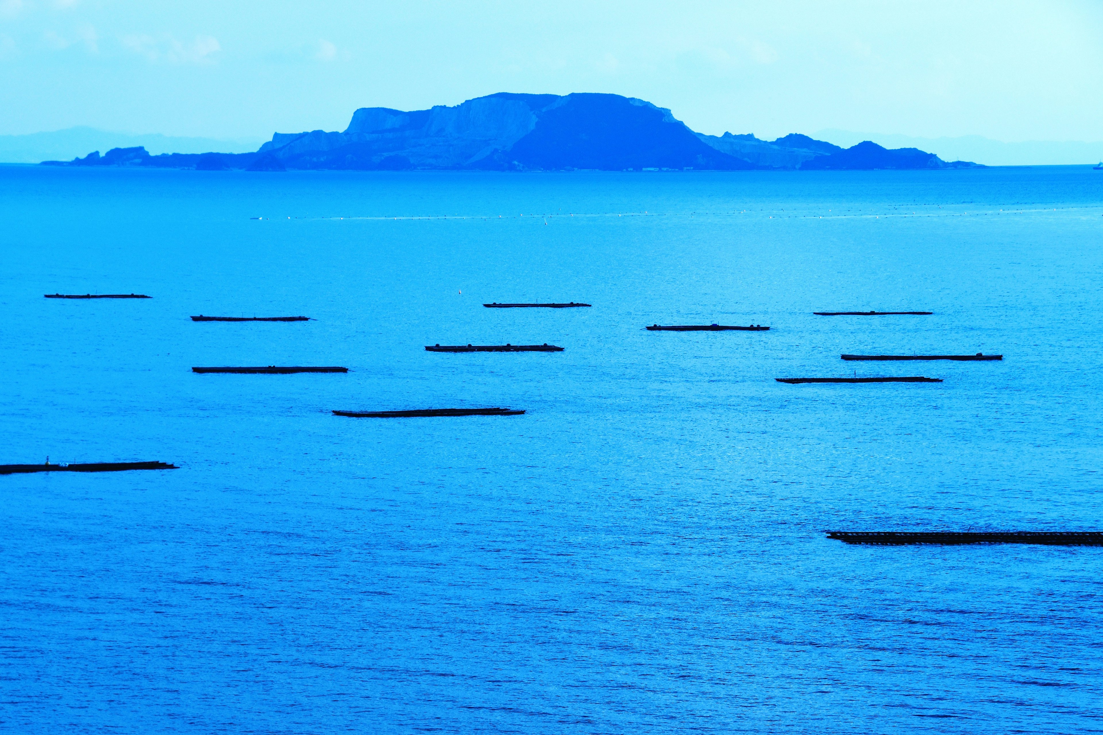 青い海と遠くの島が見える風景浮かぶ漁船