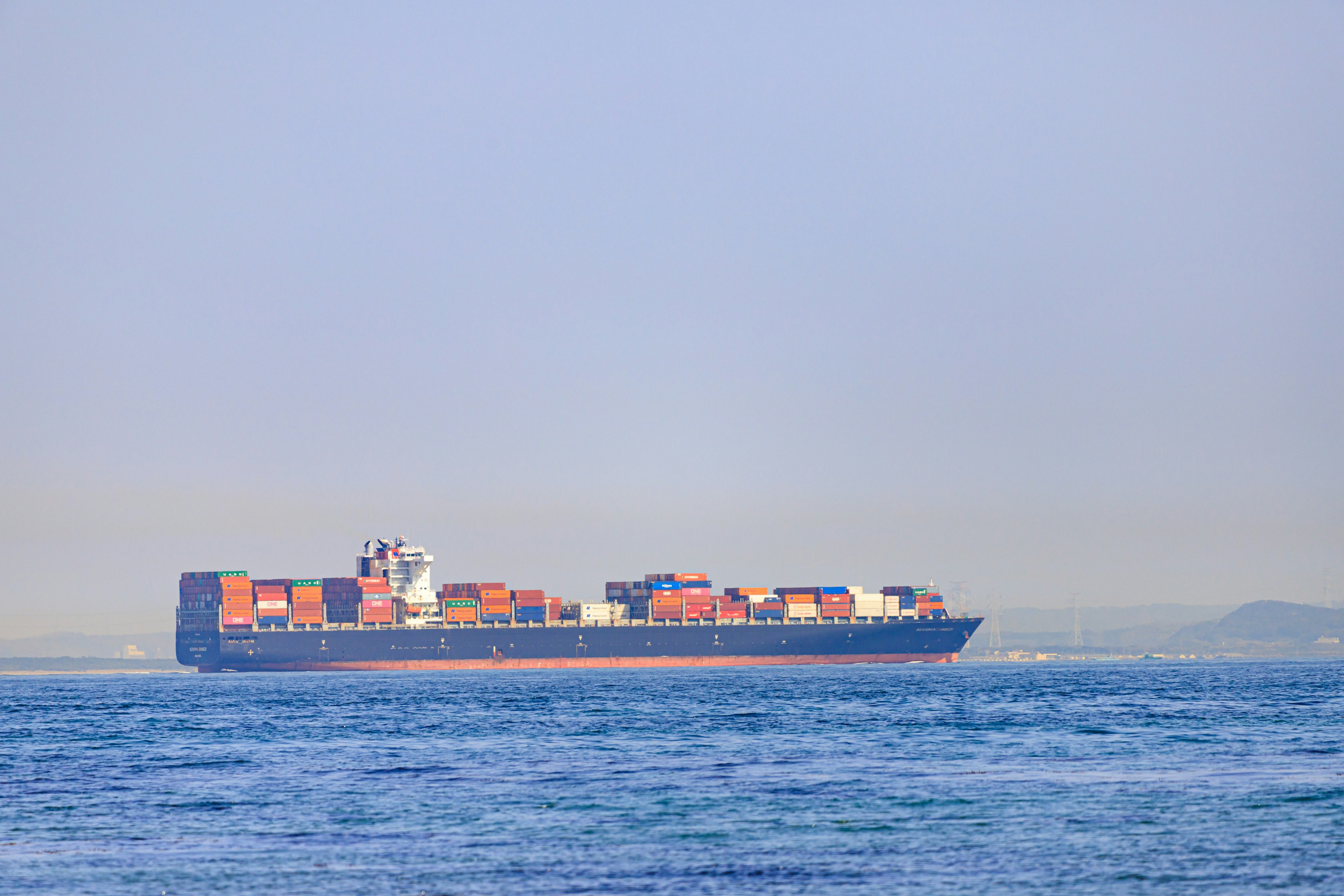 Container ship floating on blue sea under clear sky