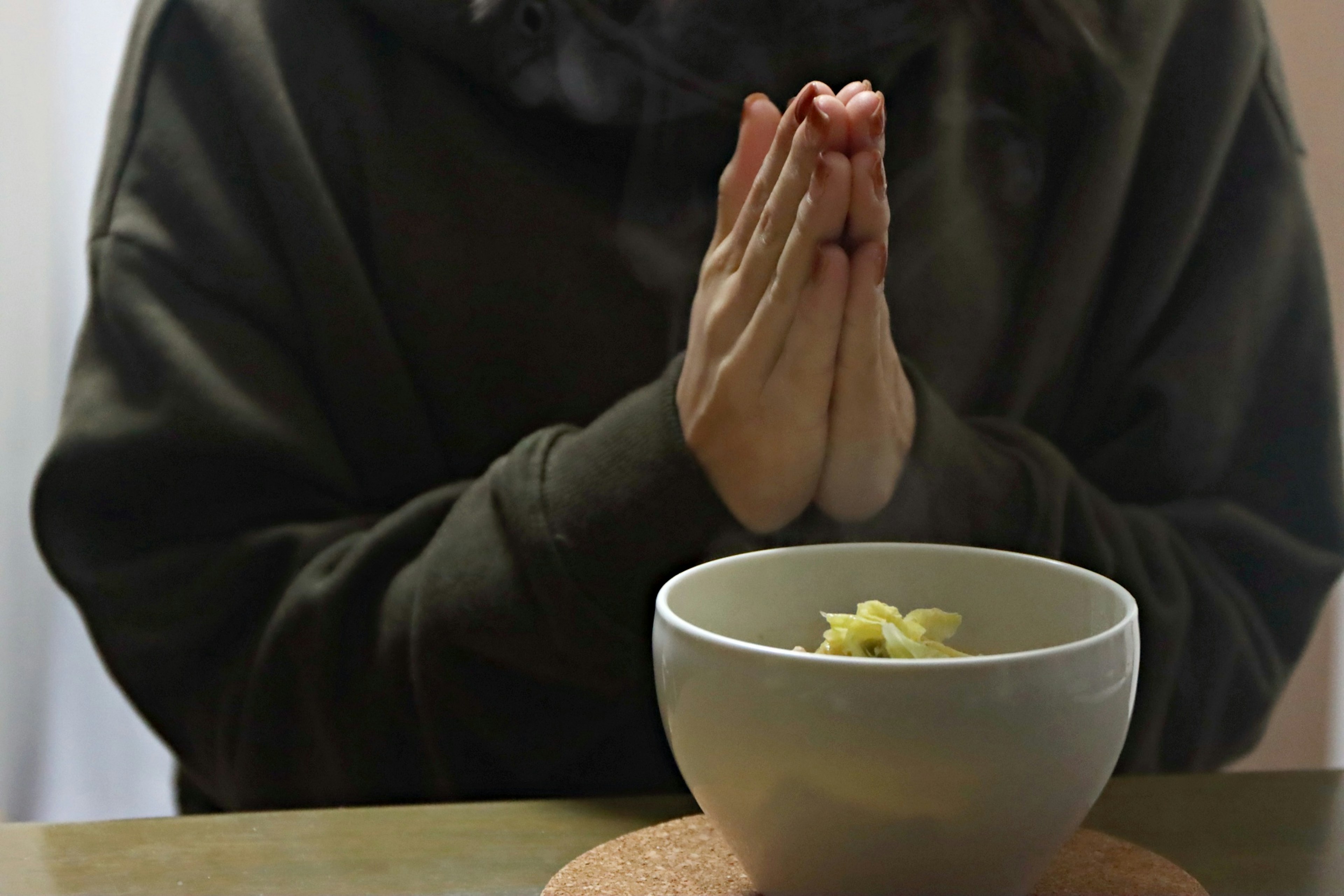 Hands in prayer position over a white bowl