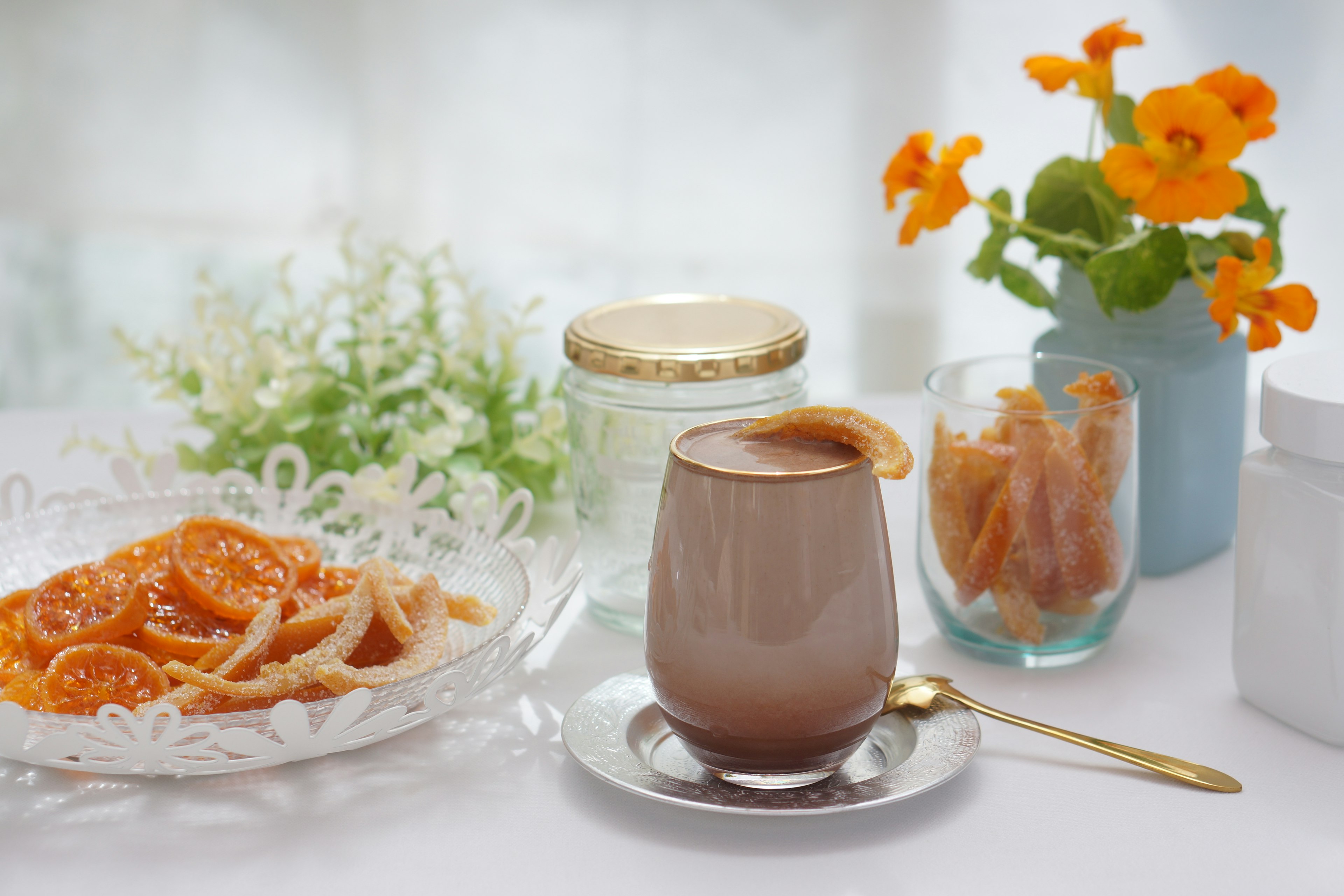 A beautifully arranged table with chocolate dessert, candied orange slices, and a vase of flowers