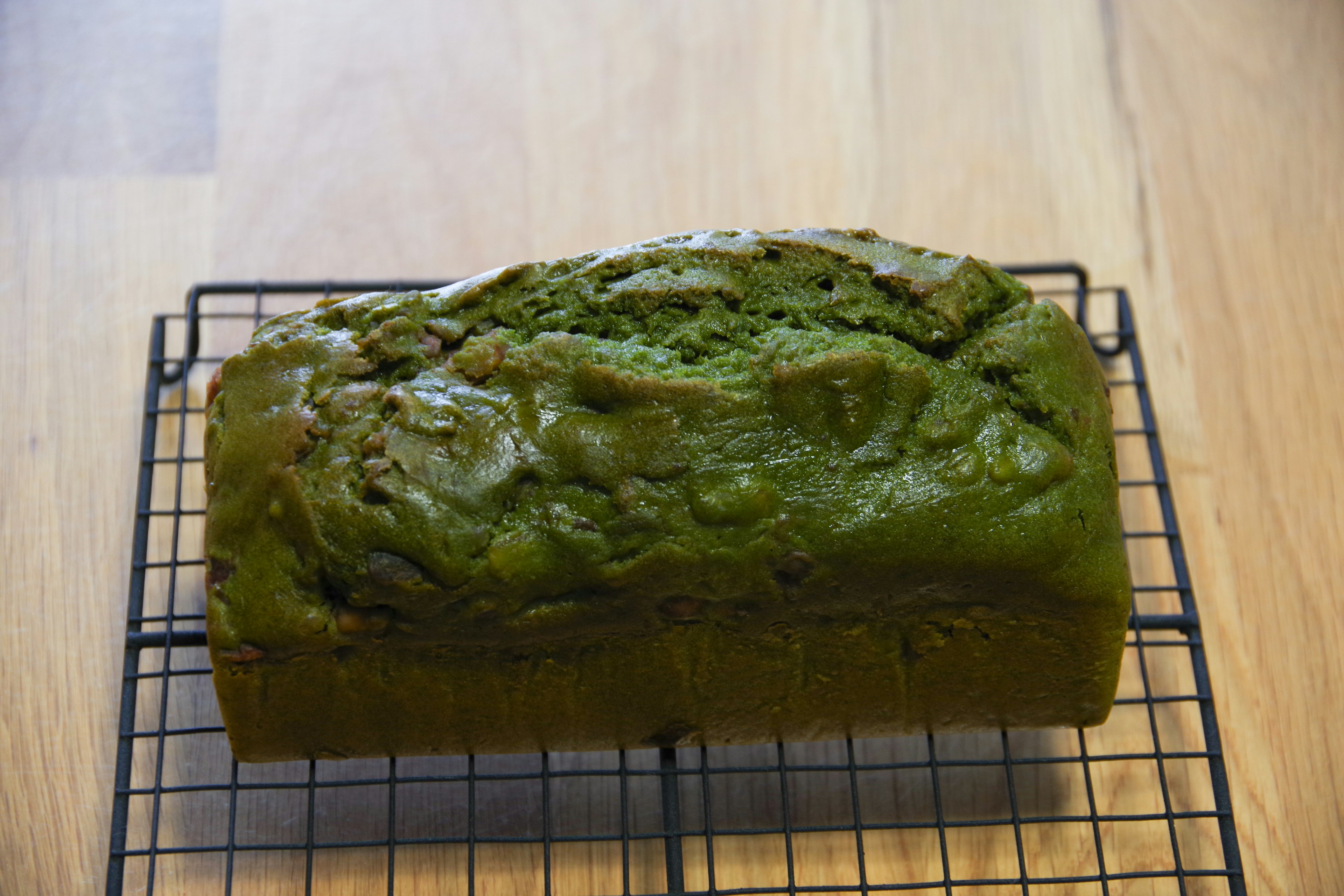 A green loaf of bread on a wire rack