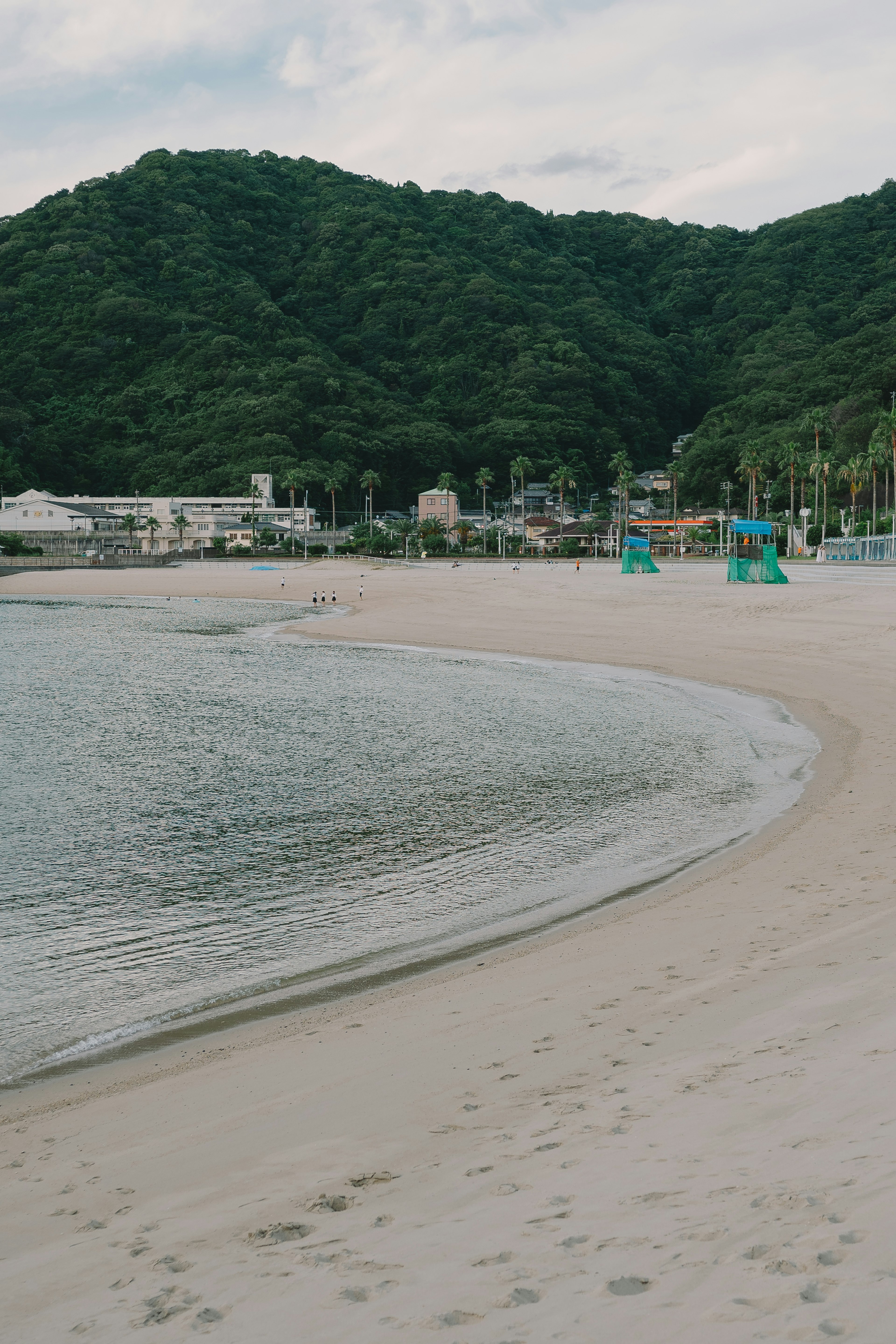 ทิวทัศน์ชายหาดที่เงียบสงบพร้อมภูเขาสีเขียวและทะเลสงบ