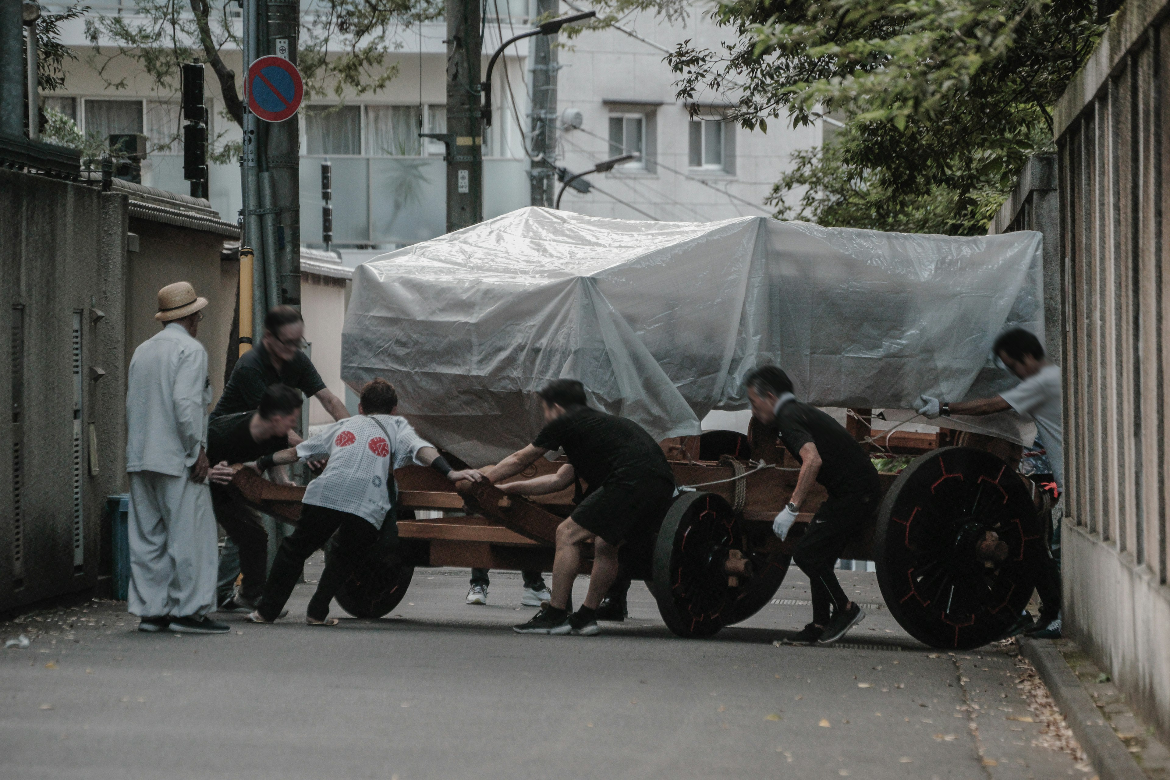 Personas empujando un carro de madera en una calle estrecha