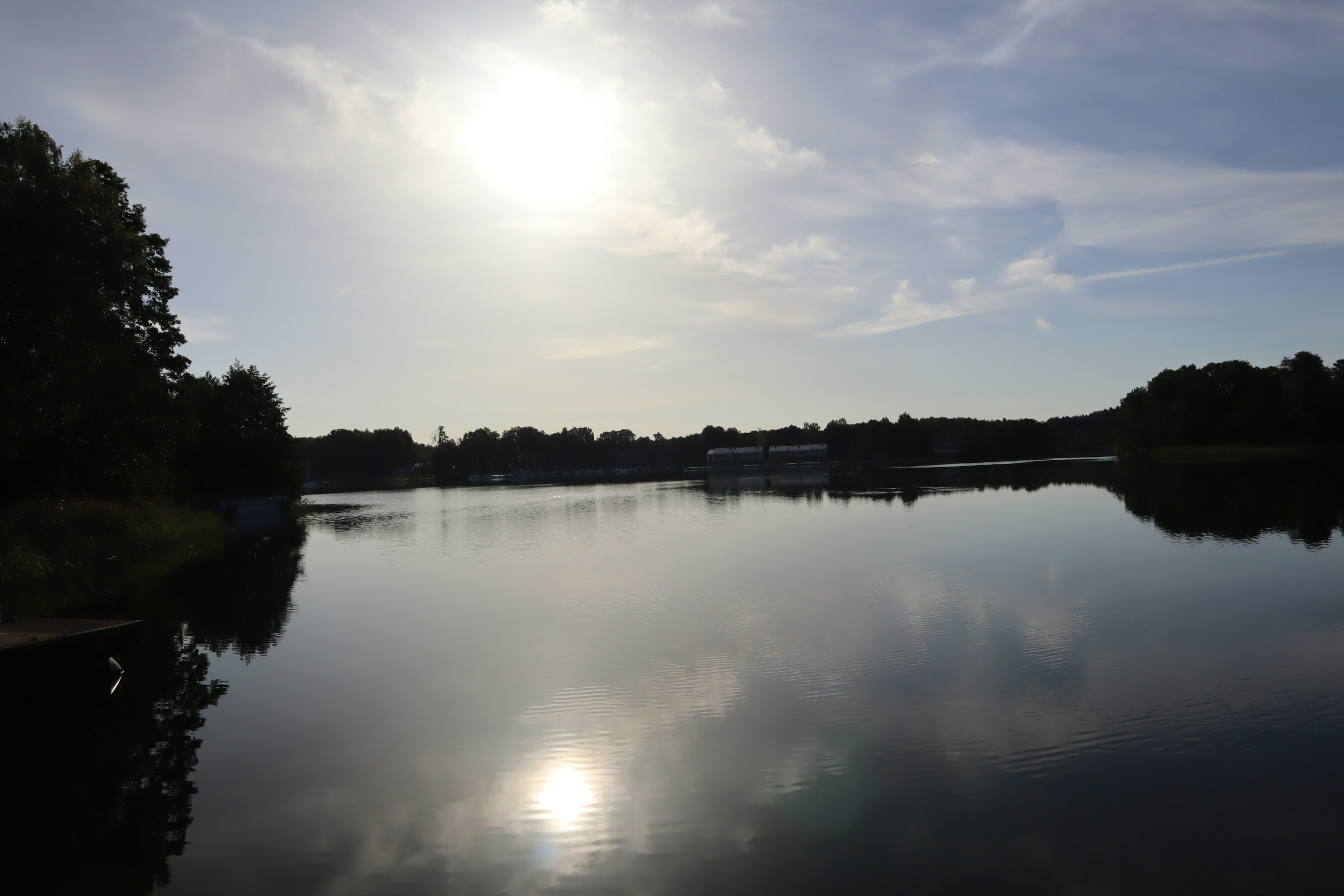 Calm lake scenery with sun reflecting on the water surface