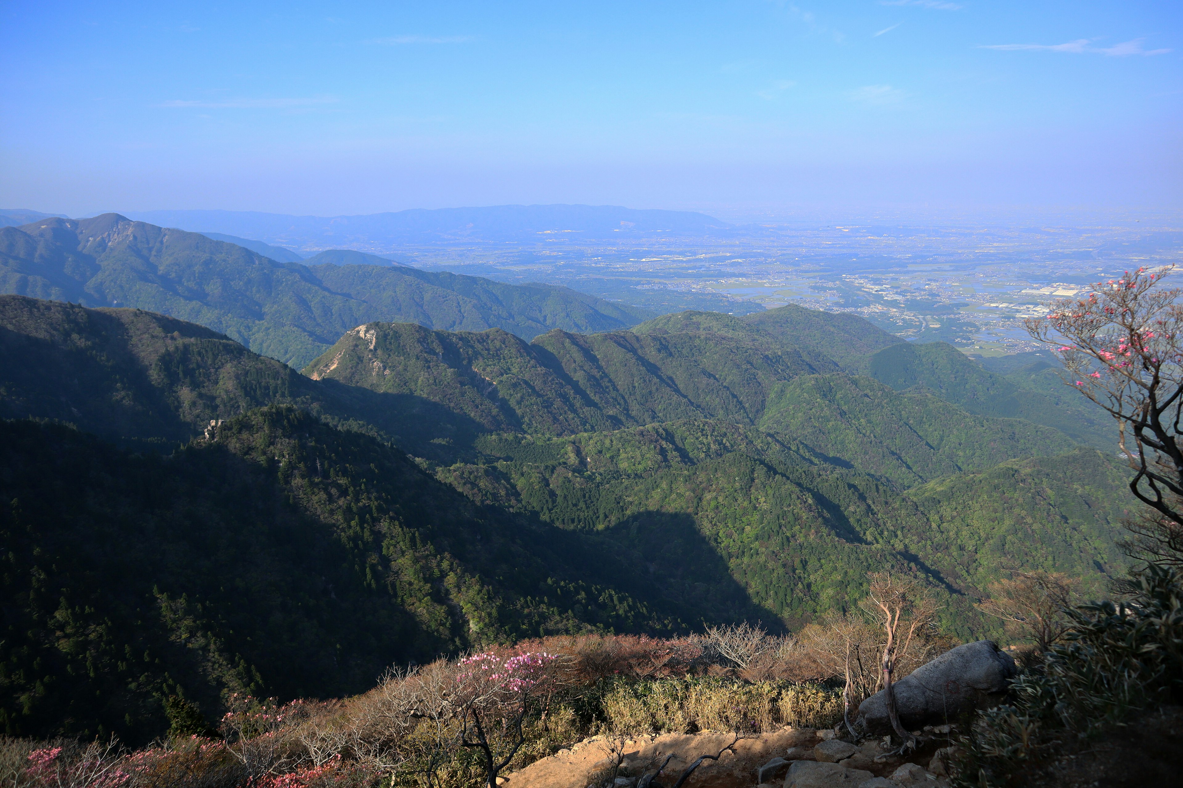 青い空の下に広がる緑豊かな山々の風景