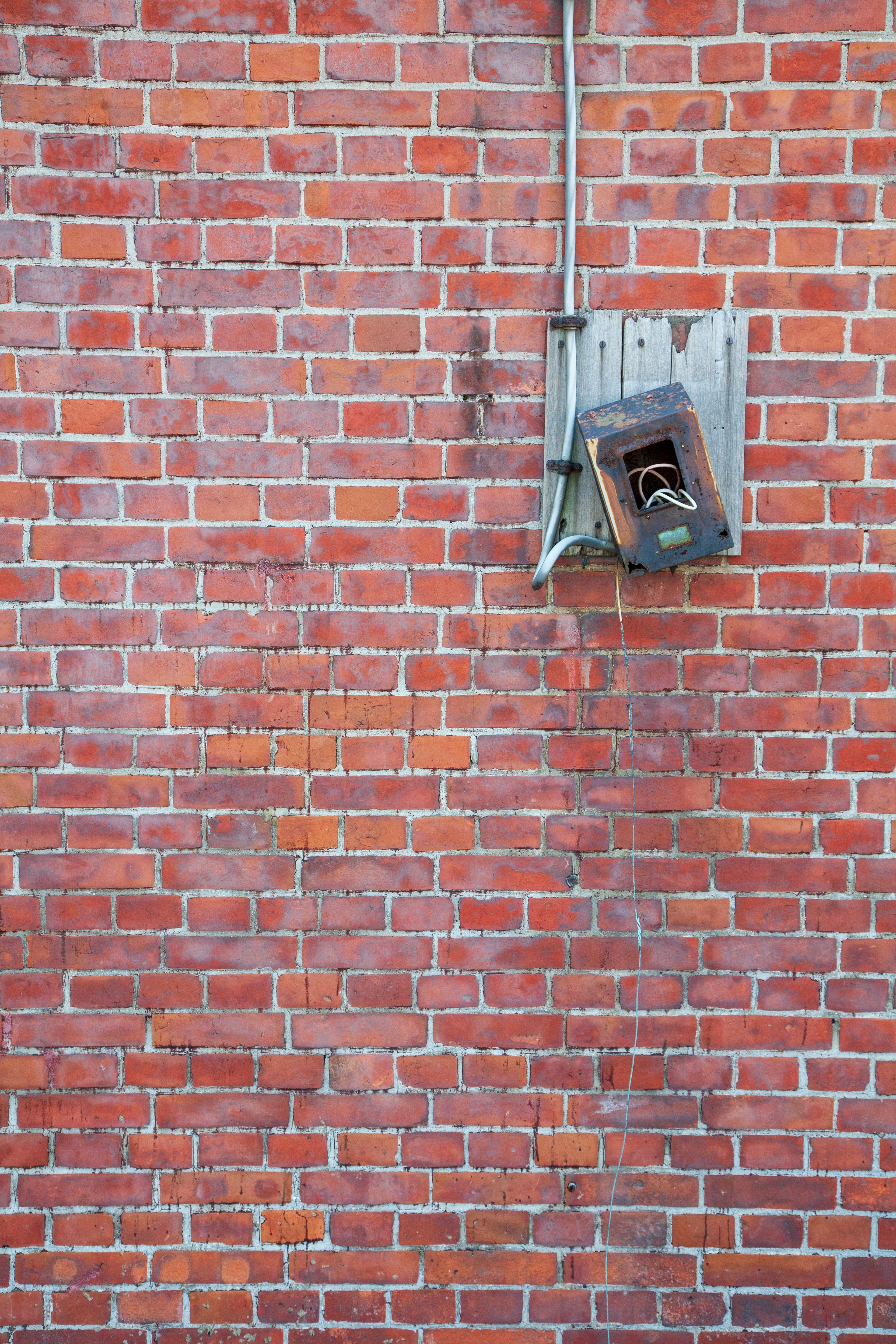 Imagen de una antigua cabina telefónica montada en una pared de ladrillos rojos