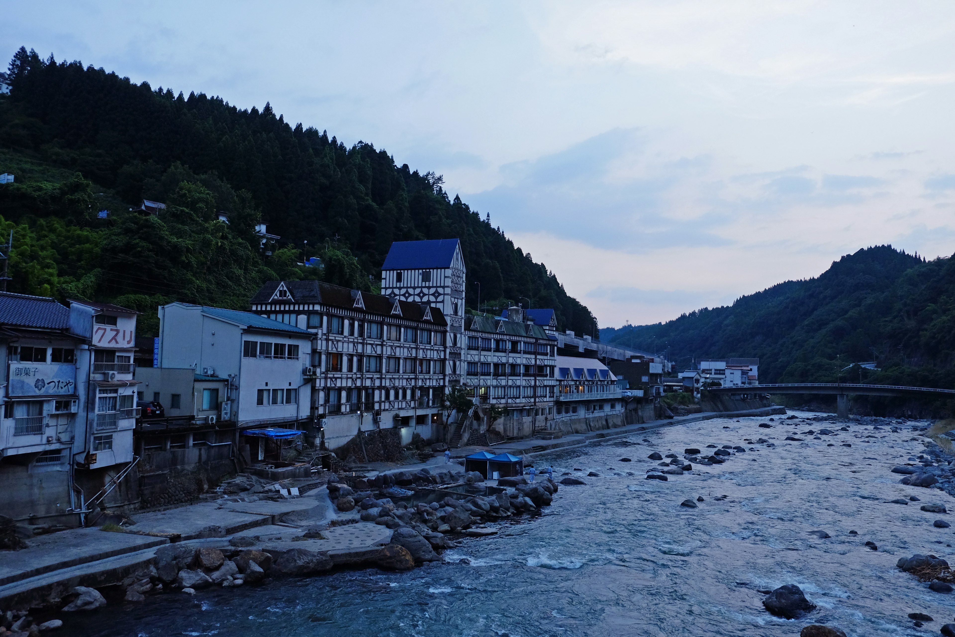 青い空の下、川沿いの宿泊施設が並ぶ風景