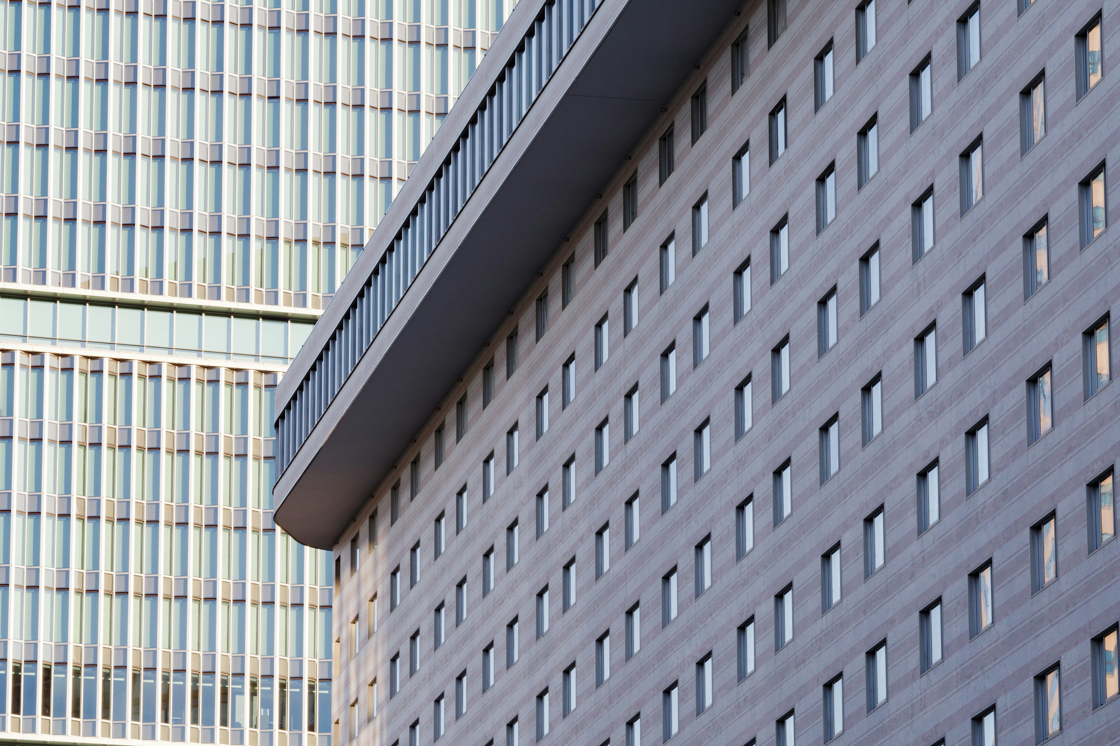 Modern building exterior with gray wall and numerous windows adjacent to a glass structure