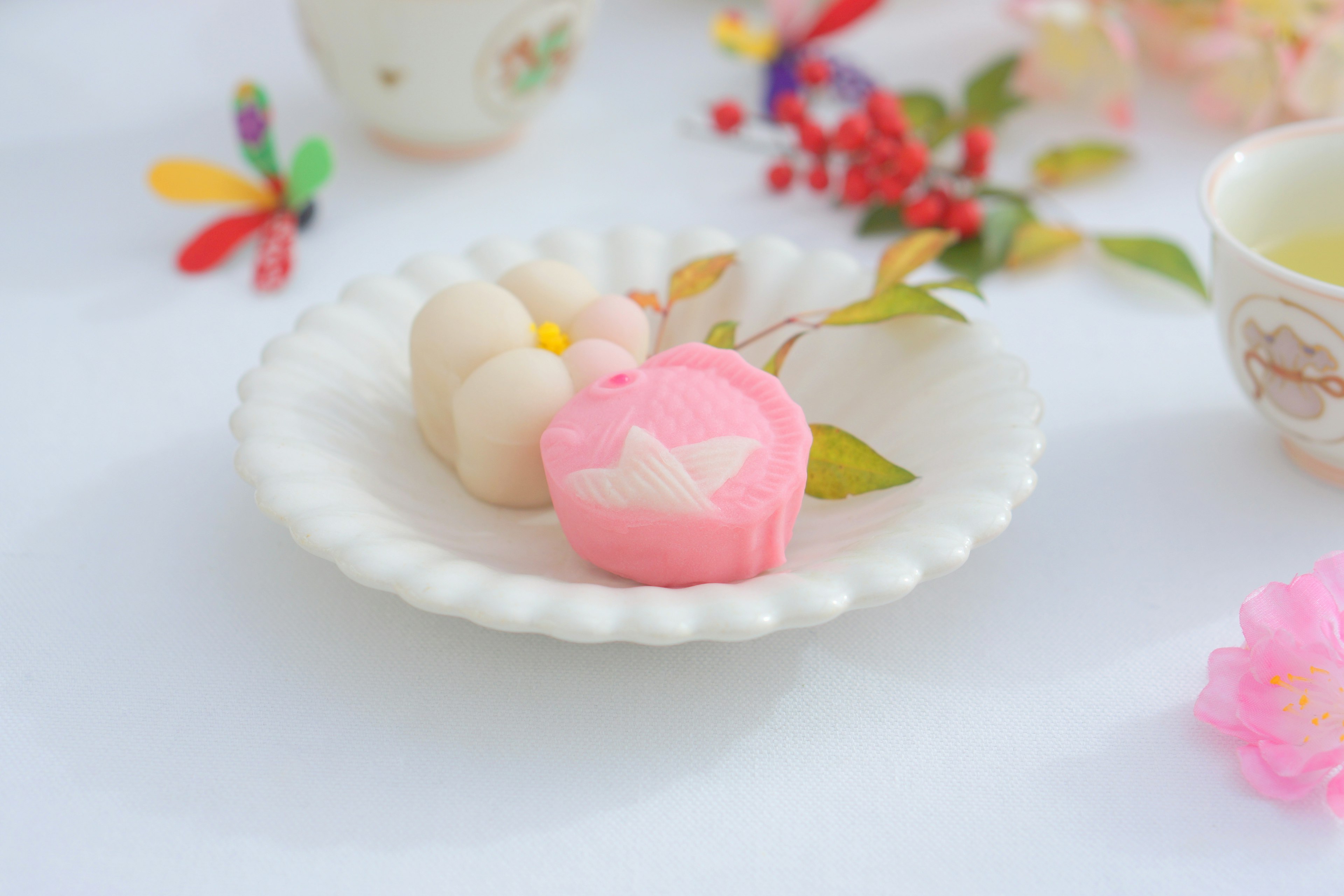 Sweets traditionnels colorés disposés sur une assiette blanche avec des feuilles vertes