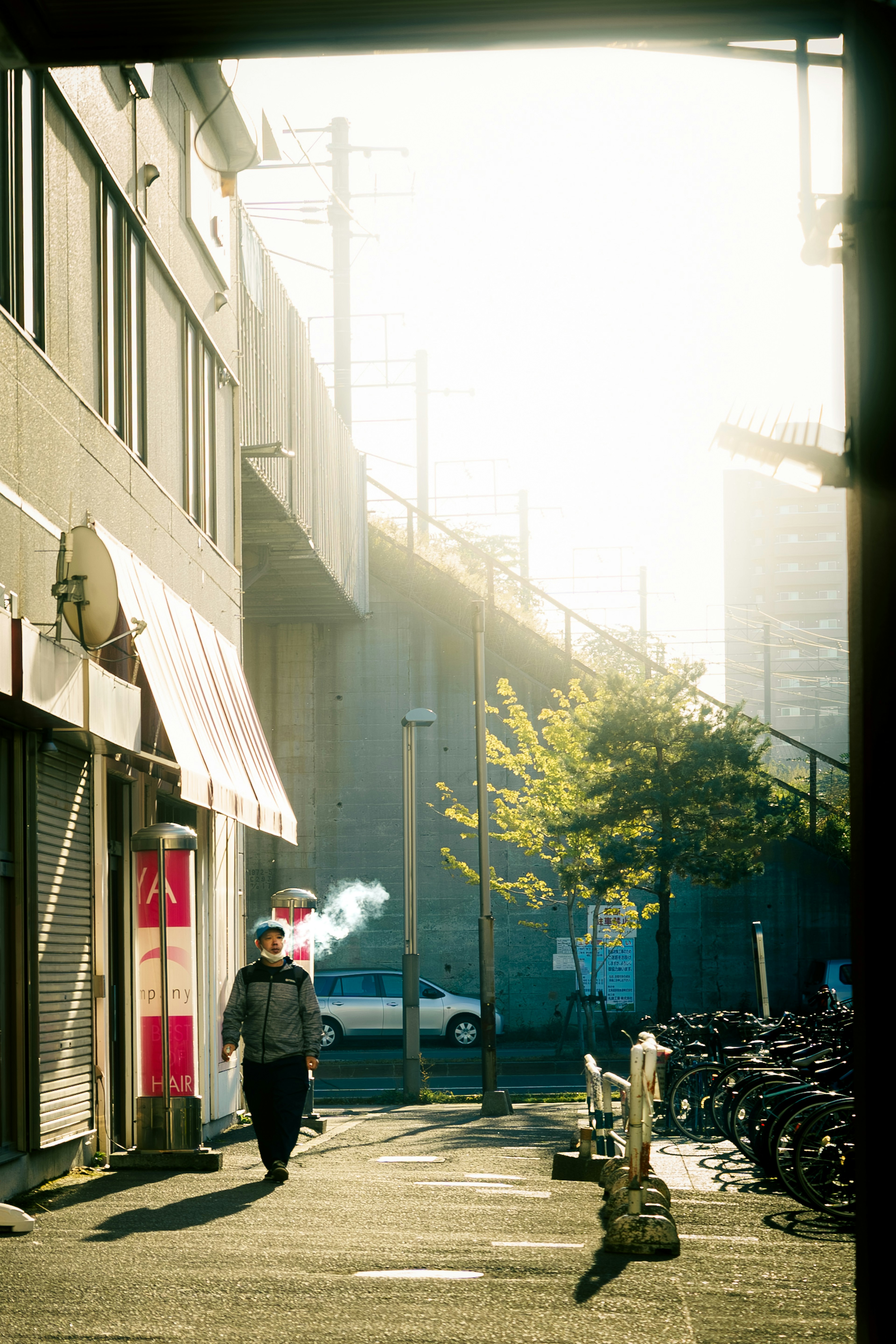 煙を吐き出しながら歩く男性と明るい背景の街並み