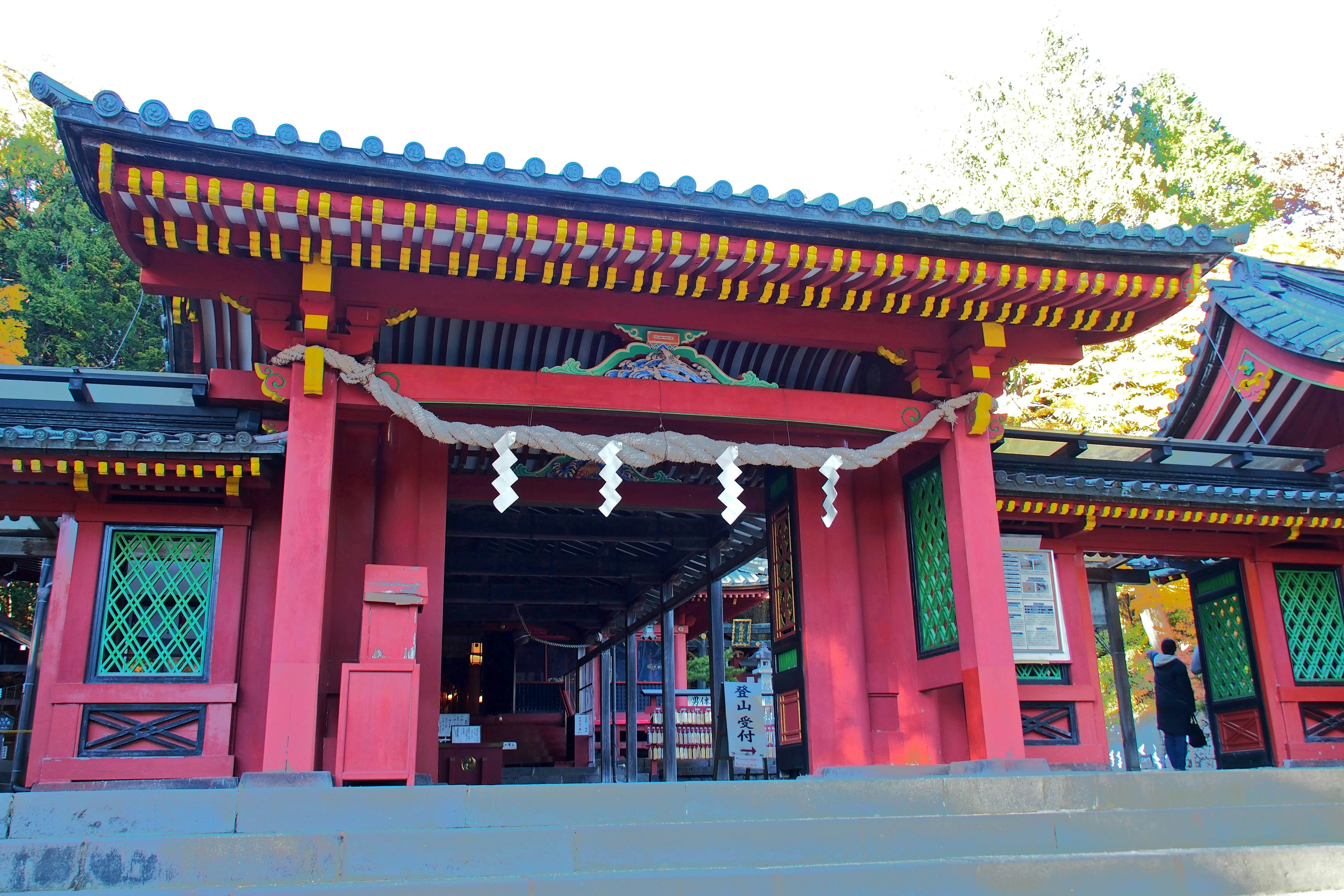 Entrance of a shrine featuring a red gate and traditional Japanese architecture