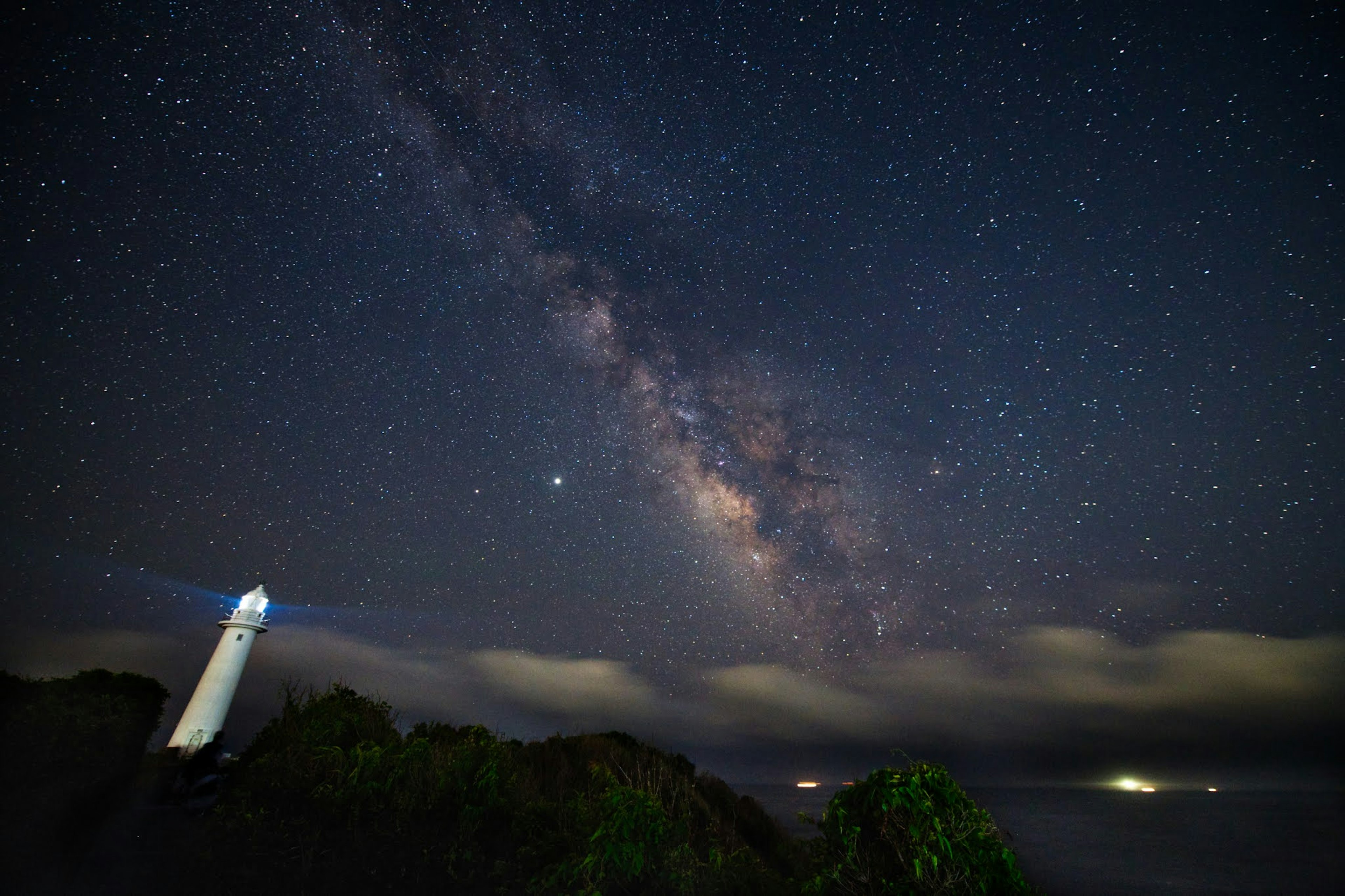 Night view of a lighthouse under a starry sky with the Milky Way