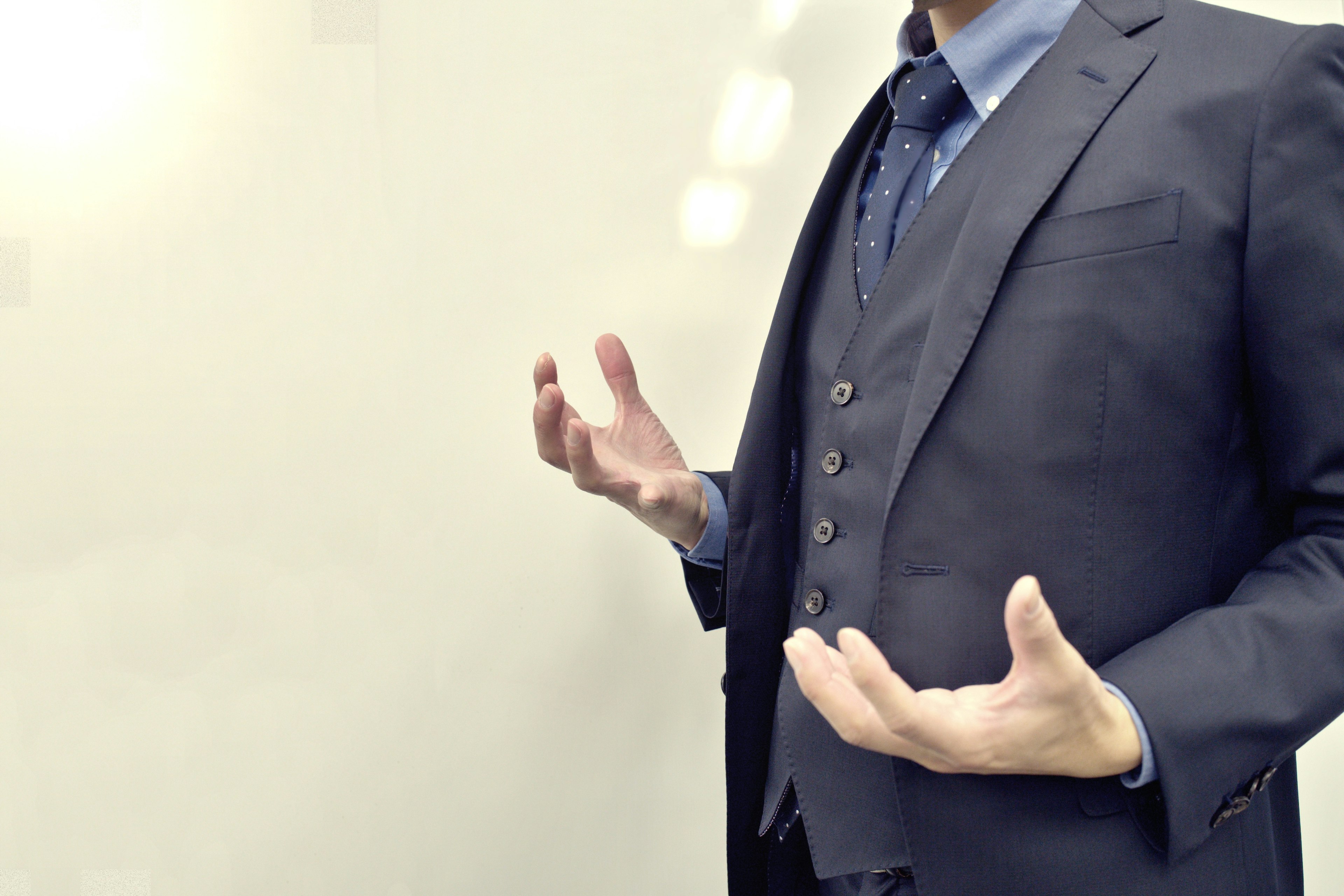 A man in a suit gesturing with open hands