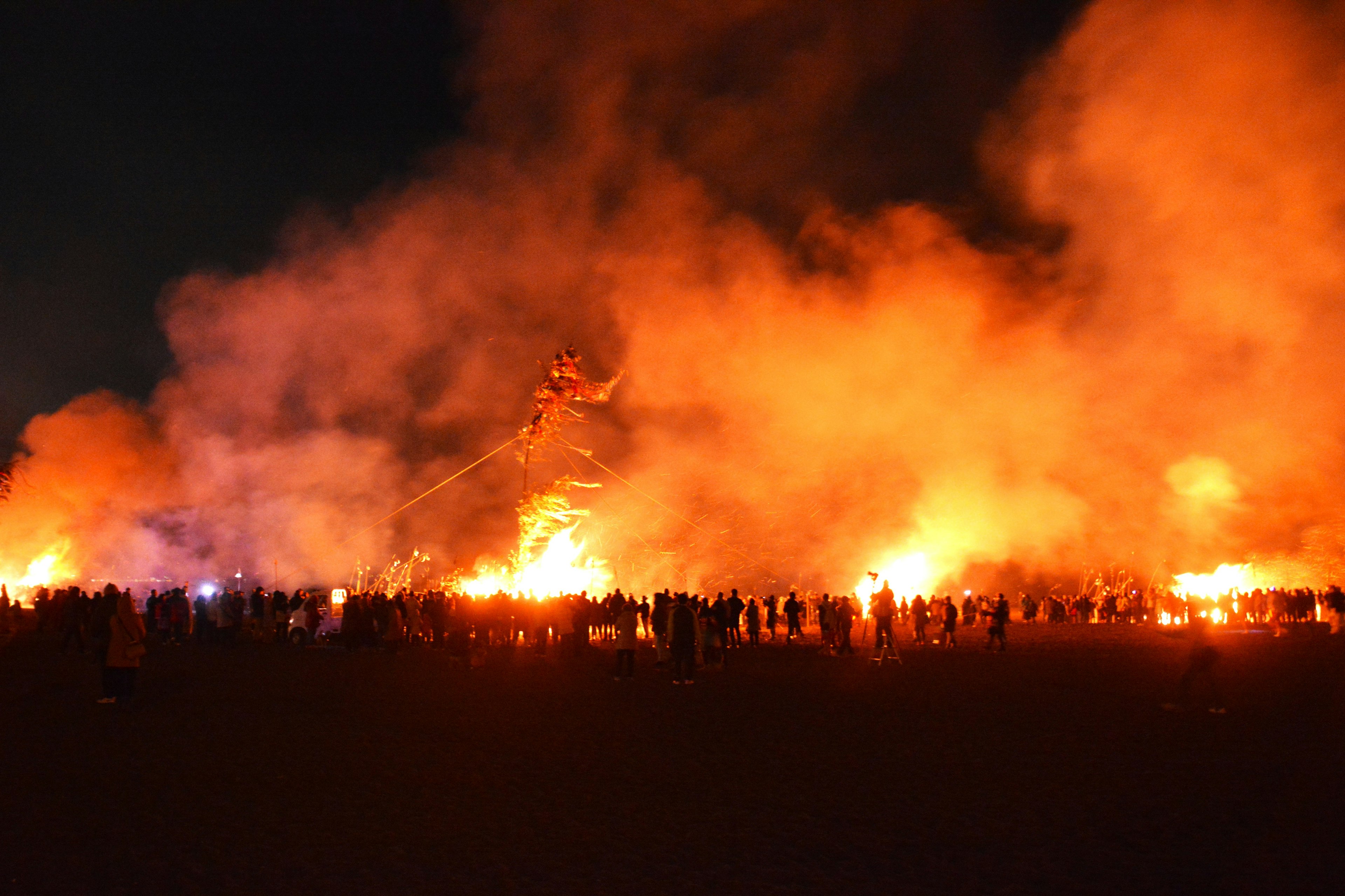 Folla di persone illuminata da fiamme e fumi di notte