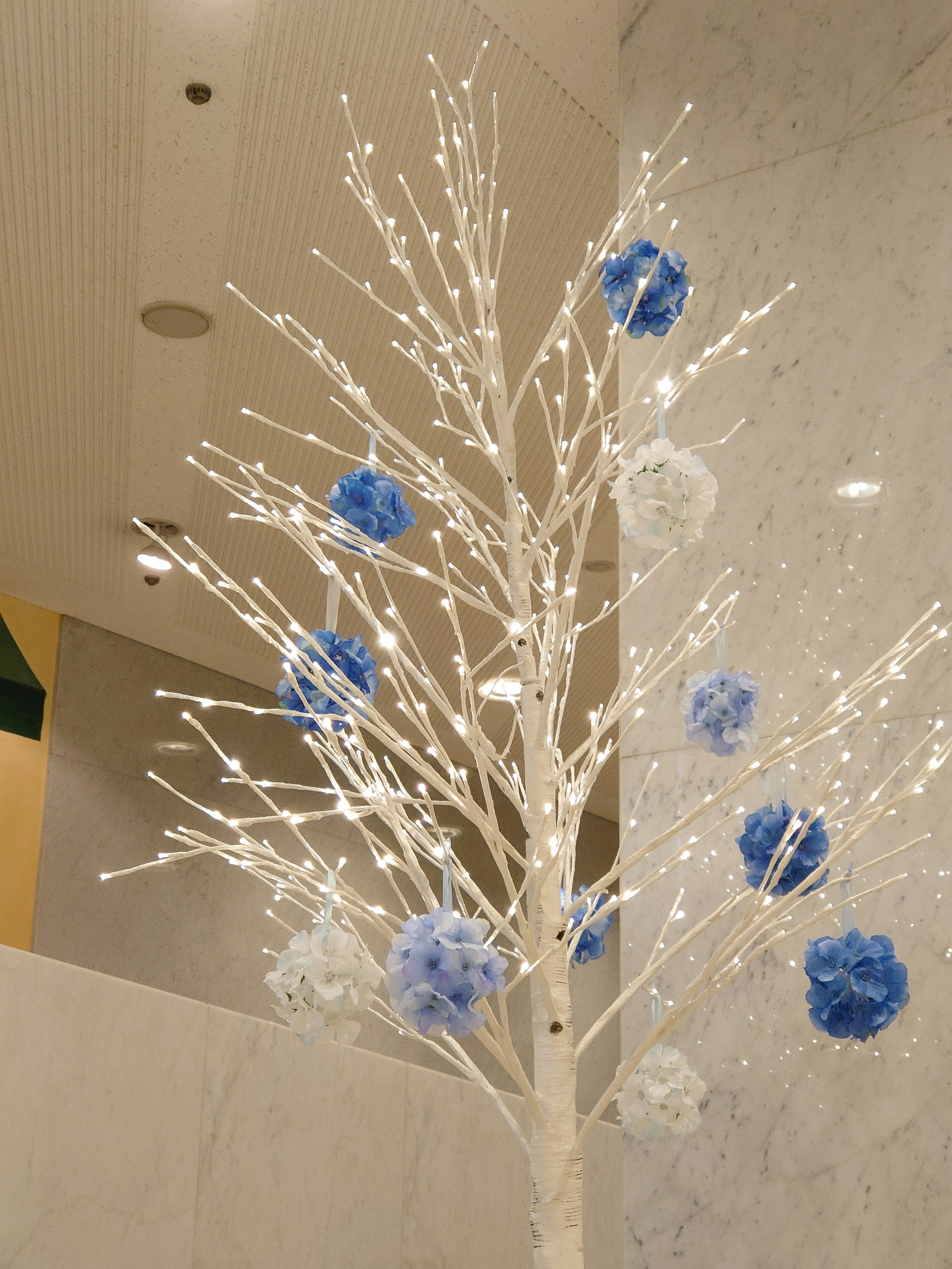 Decorative white tree adorned with blue and white pom poms