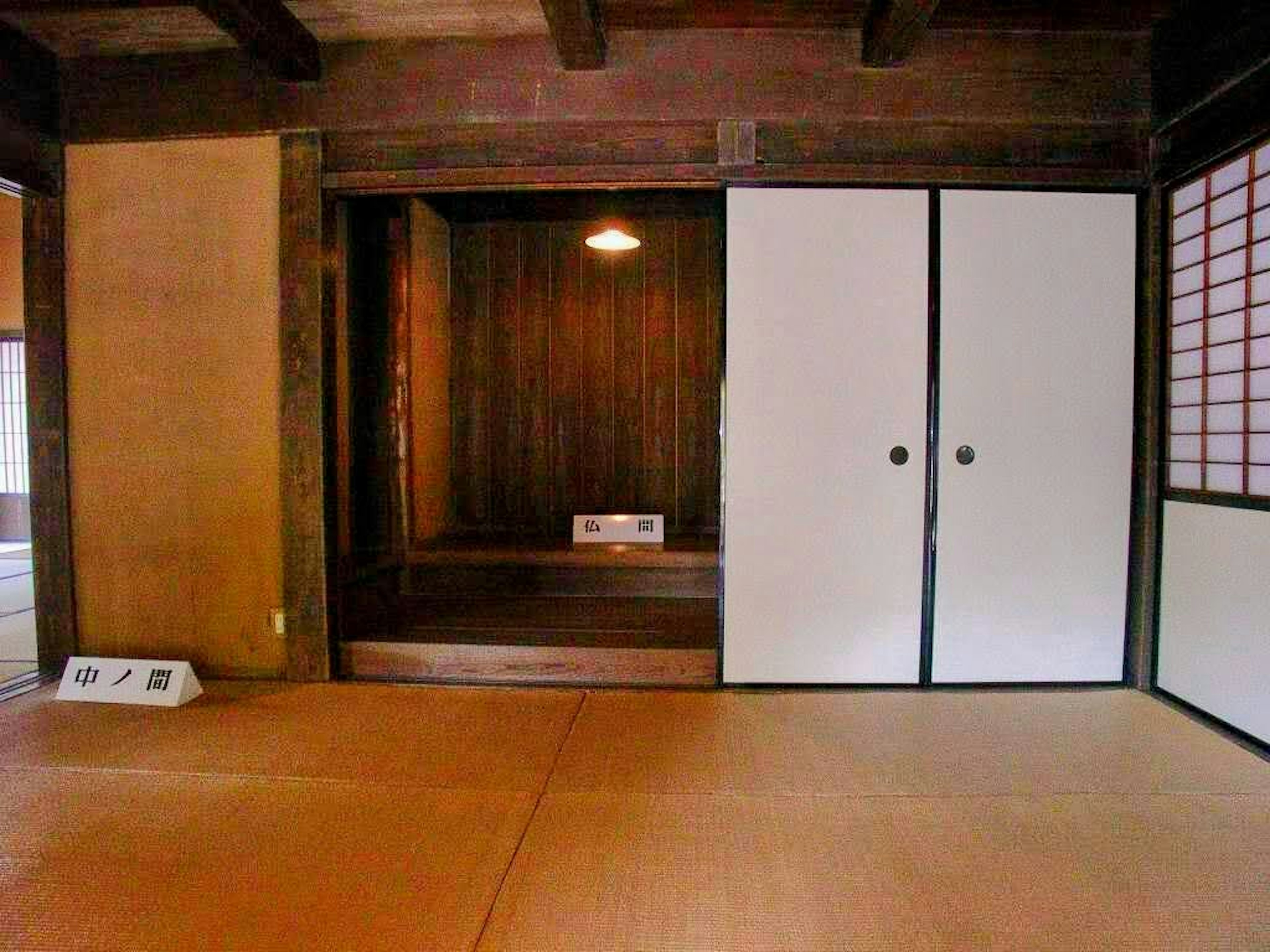 Interno di una stanza giapponese tradizionale con pavimento in tatami porte scorrevoli bianche travi in legno alcova scura