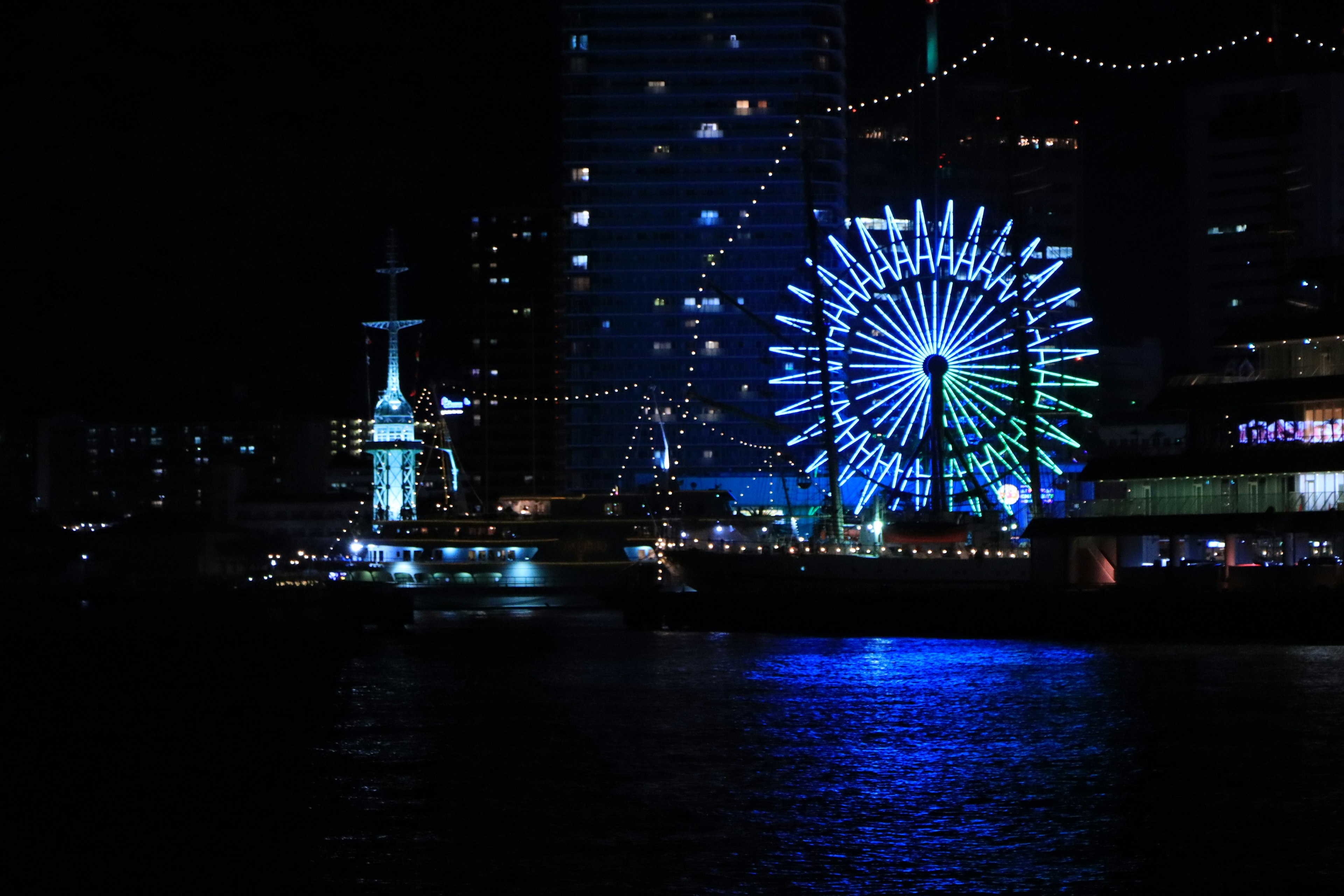 Night view of a brightly lit ferris wheel and harbor